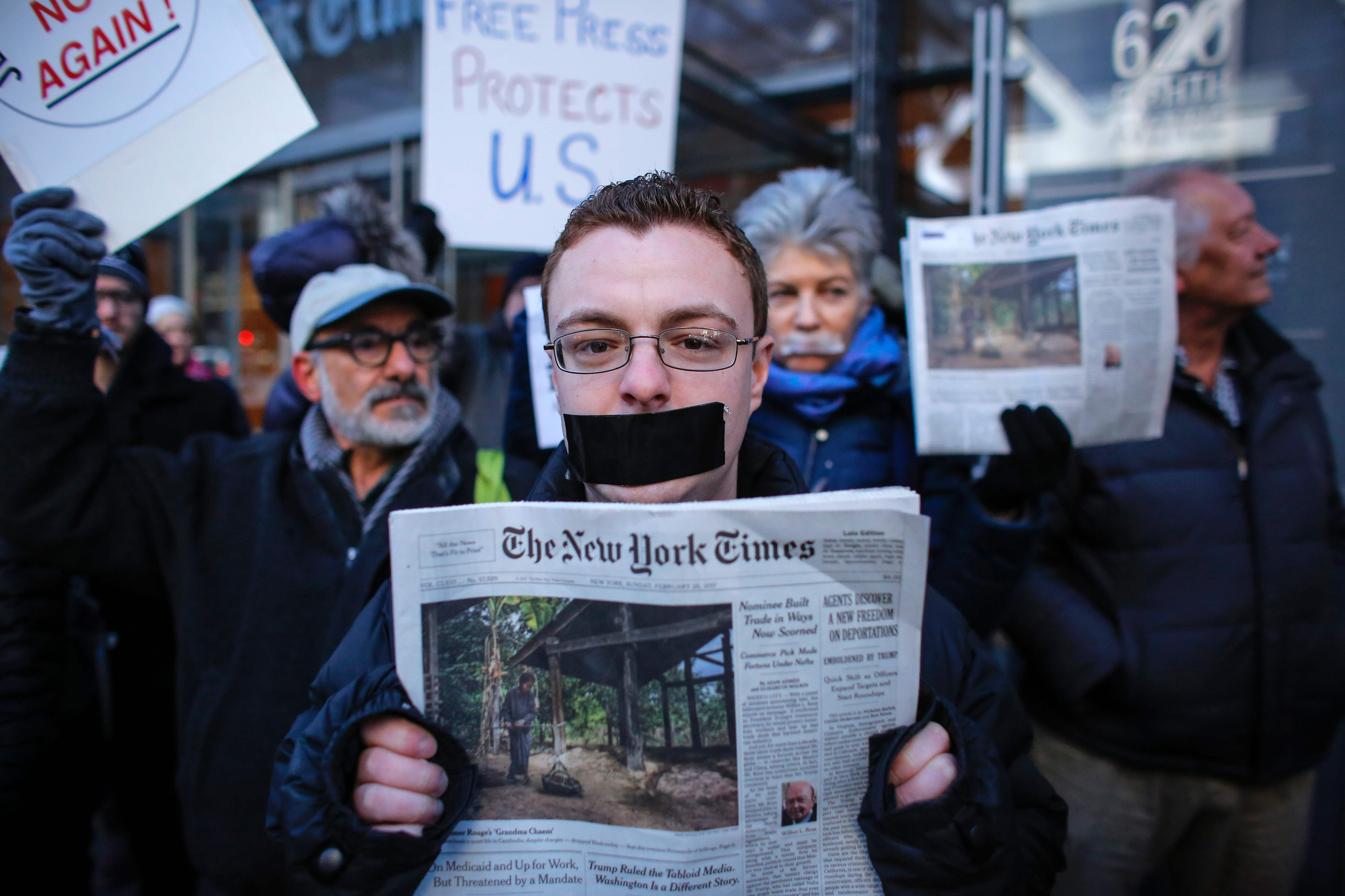 شاب يكمم فاهه ويمسك فى يده نسخة ورقية لصحيفة نيويورك تايمز فى مظاهرة لدعم الصحافة
