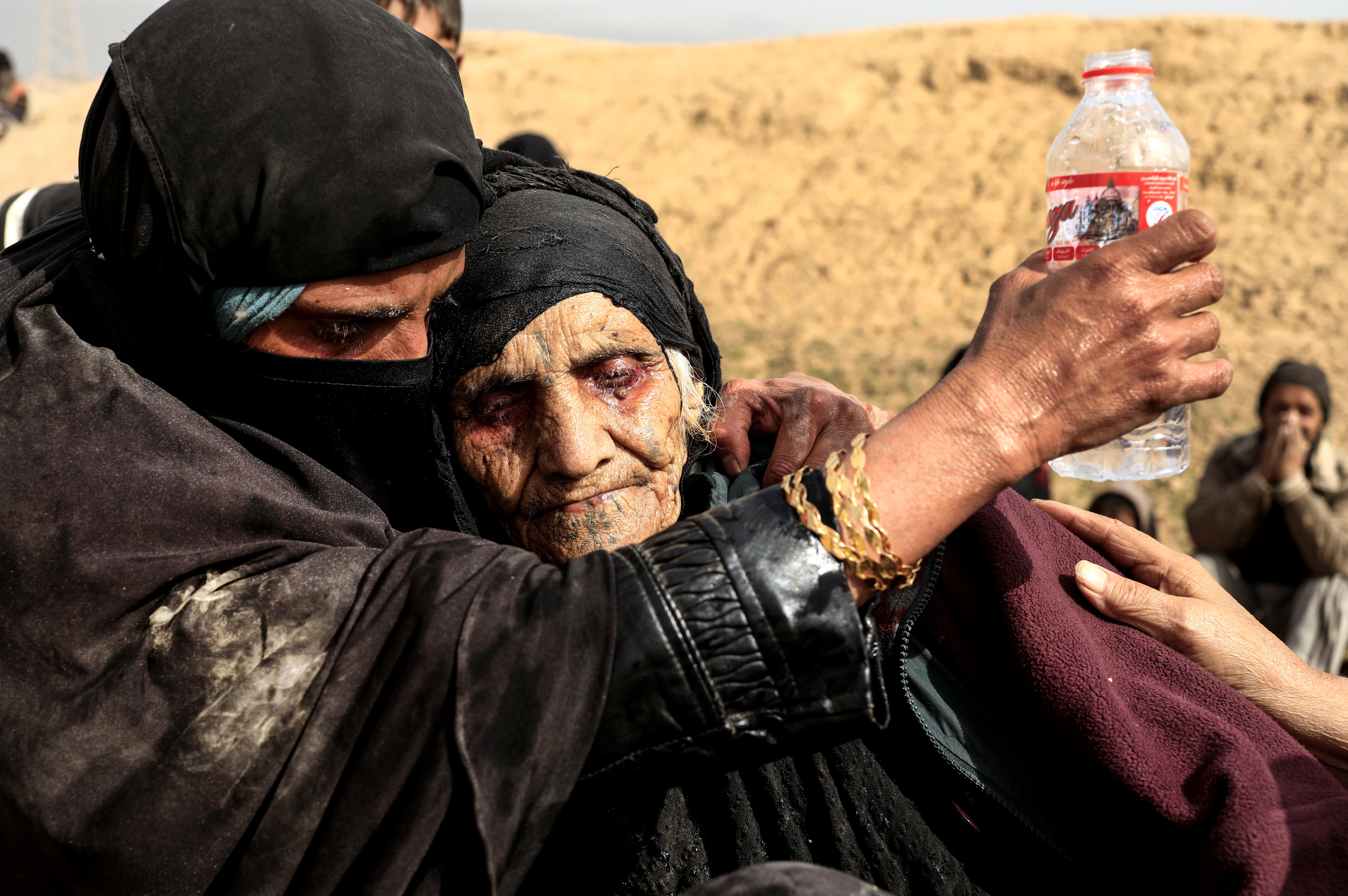 سيدة تساعد عجوز على الشرب بعد الهروب من داعش فى الموصل