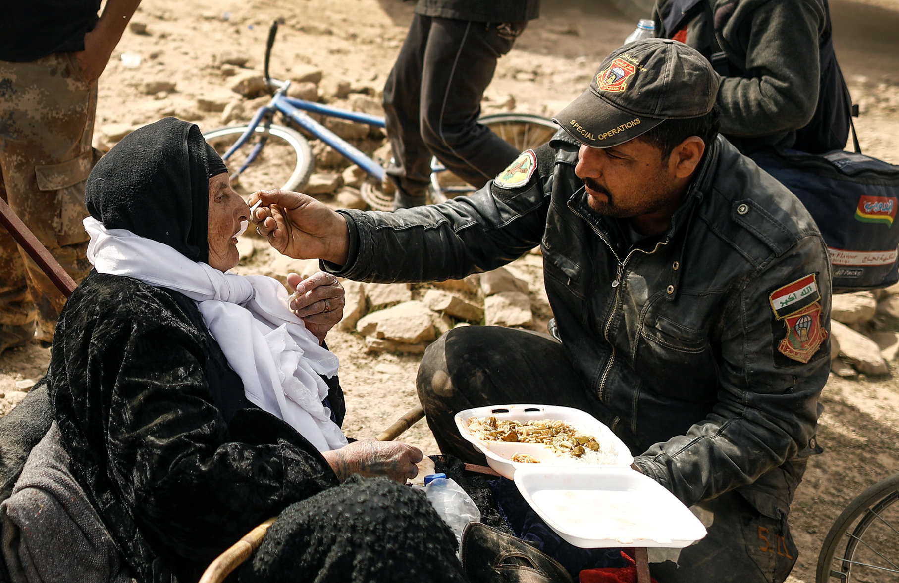 أحد أفراد القوات الخاصة العراقية يطعم سيدة عجوز داخل قاعدة عسكرية
