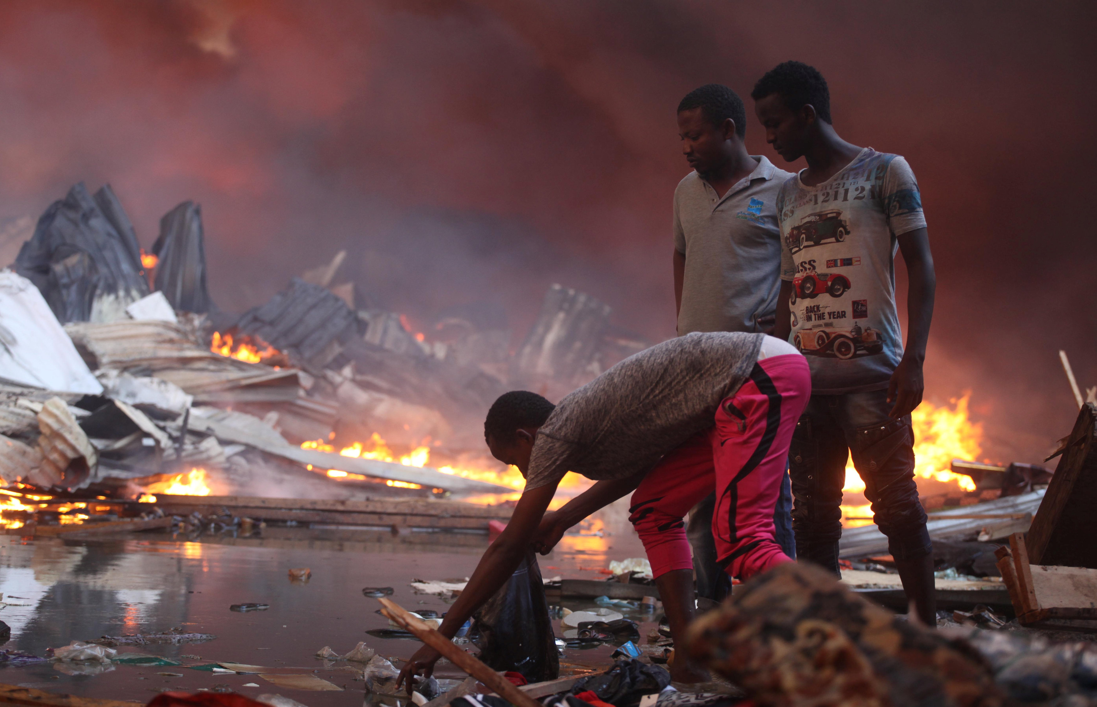 شباب ينتشلون متعلقاتهم من وسط المياه خارج سوق محترق فى الصومال