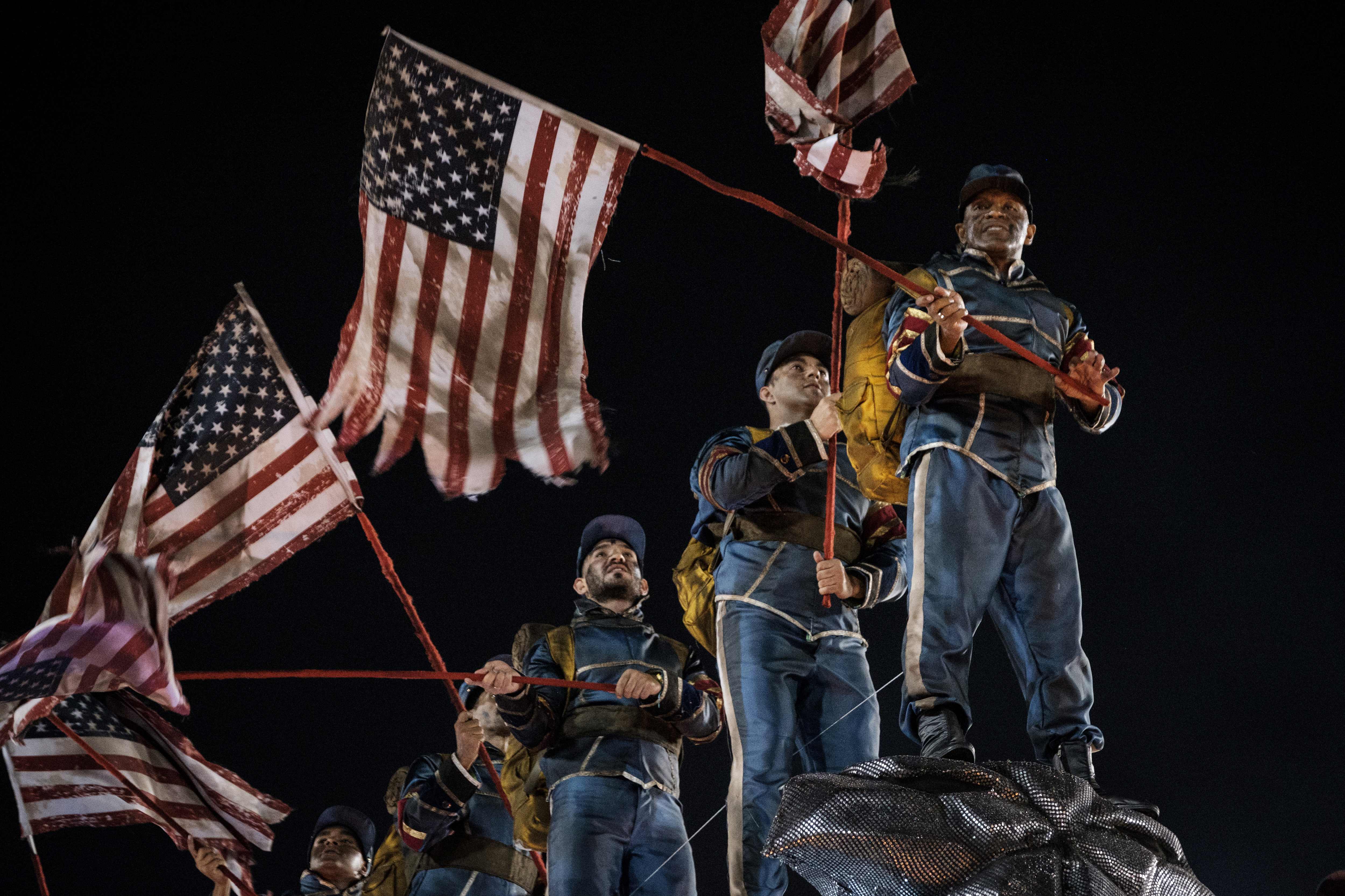 شباب يرفعون علم أمريكا خلال أحد عروض كرنفال السامبا