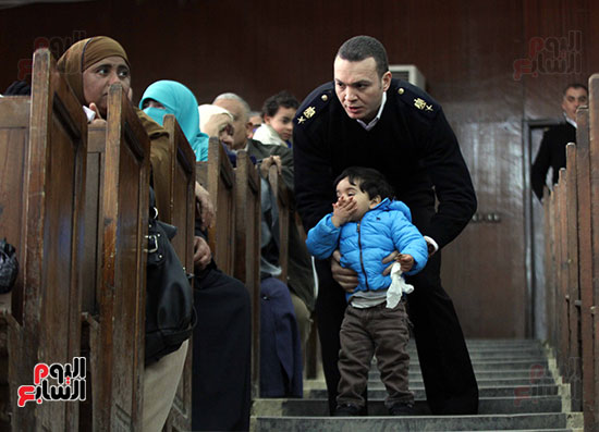 ضابط يسلم أحد أطفال المتهمين إلى ذويه بالقاعة