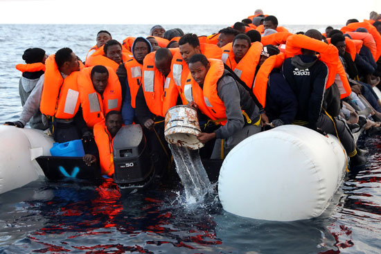 بعض المهاجرين فى محاولة لإنقاذ الزورق المطاطى من الغرق