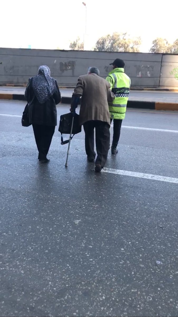 شرطى المرور خلال مساعدة مواطنين لعبور الشارع شرطى المرور خلال مساعدة مواطنين لعبور الشارع