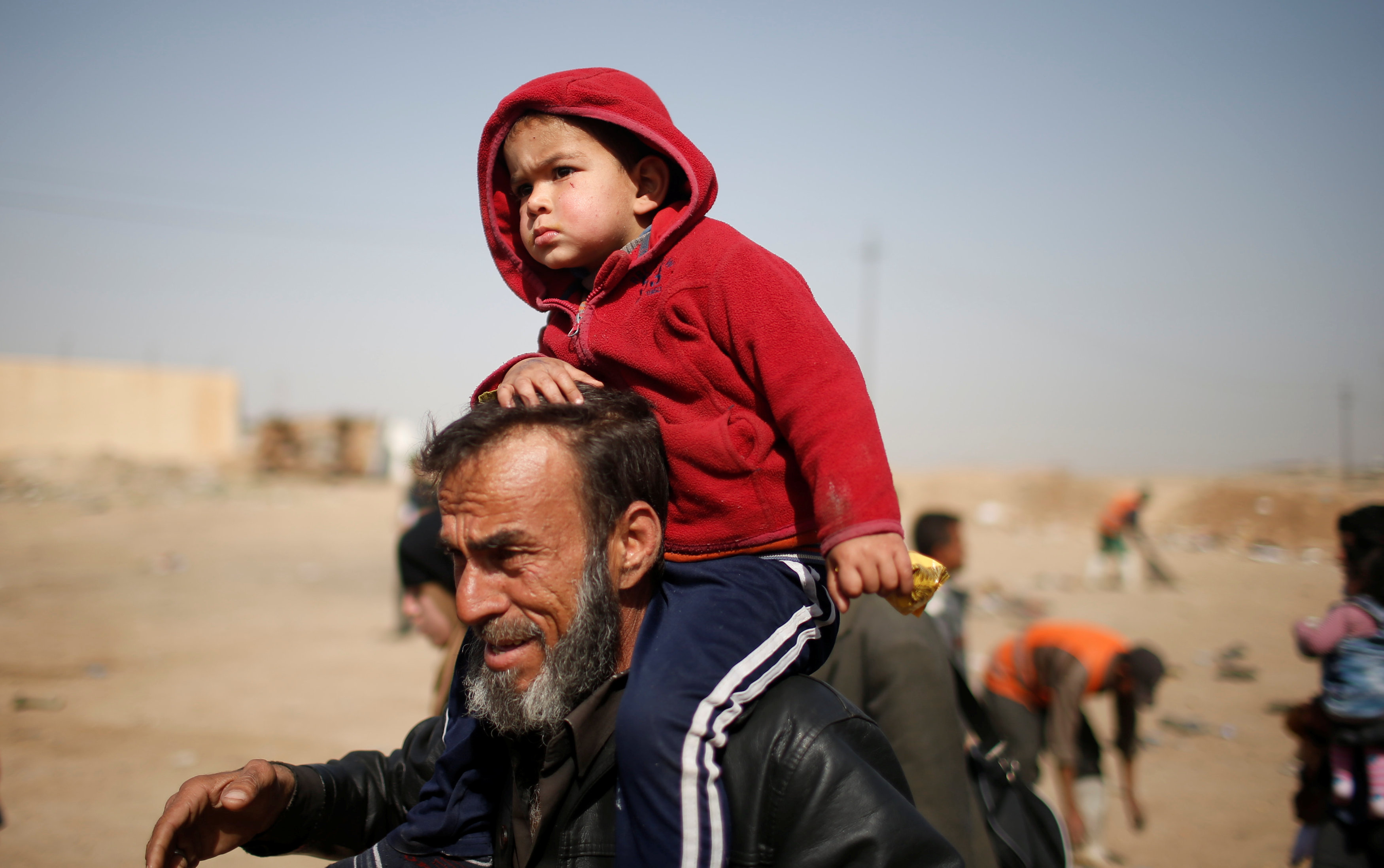 رجل يحمل ابنه على كتفه خلال النزوح من الموصل
