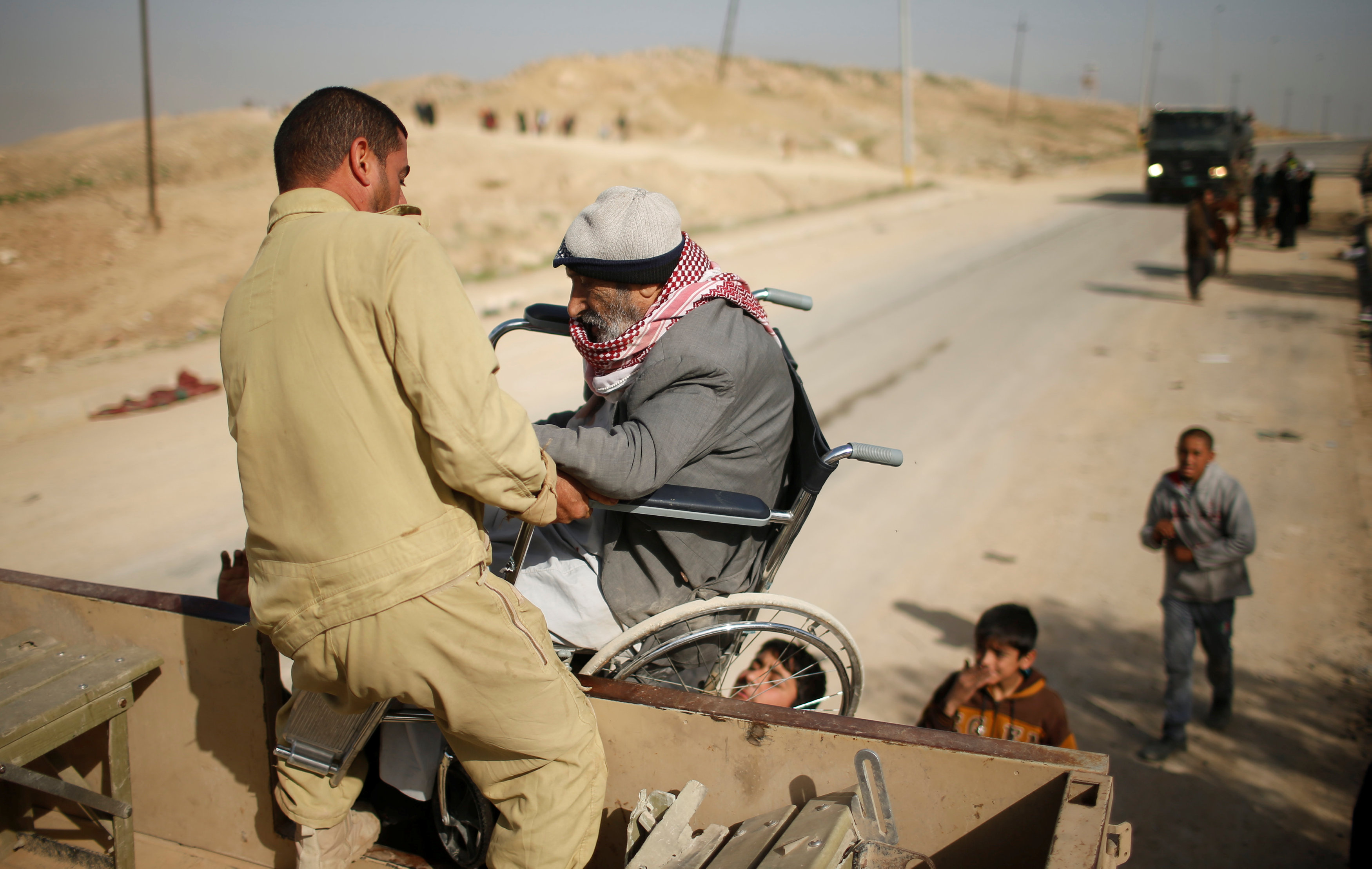 مواطنون يساعدون رجل قعيد على الصعود للسيارة للهرب من داعش