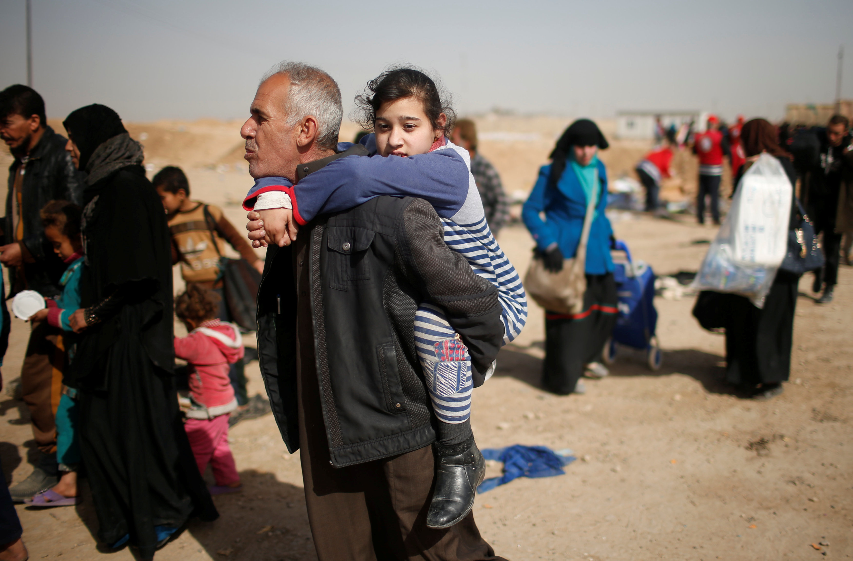 رجل يحمل ابنته على ظهره للنزوح باتجاه معسكرات الجيش فى الموصل