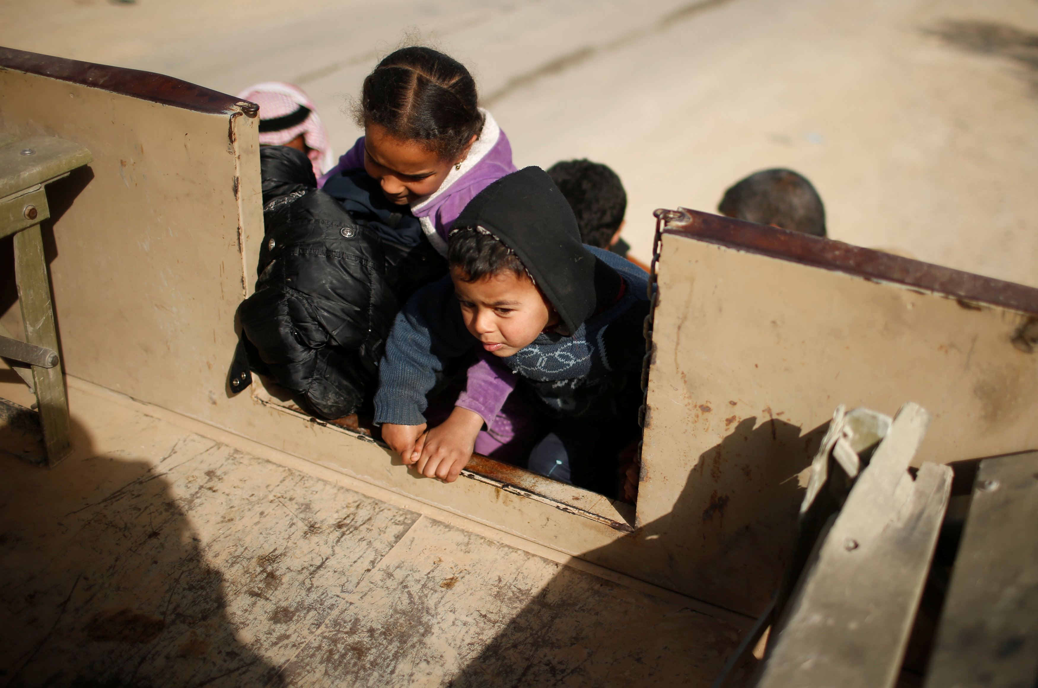 الأطفال يصعدون للسيارات للانتقال لمعسكرات الايواء بالموصل