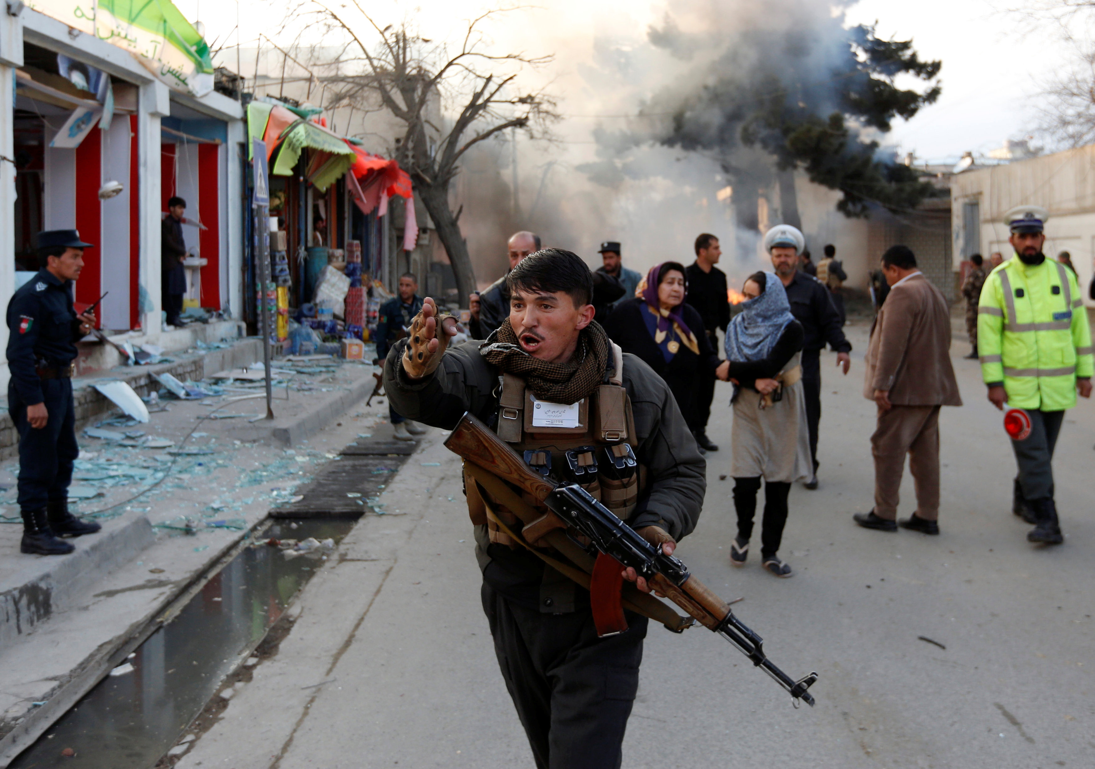 أحد أفراد الشرطة الأفغانية يبعد المدنيين عن موقع الانفجار
