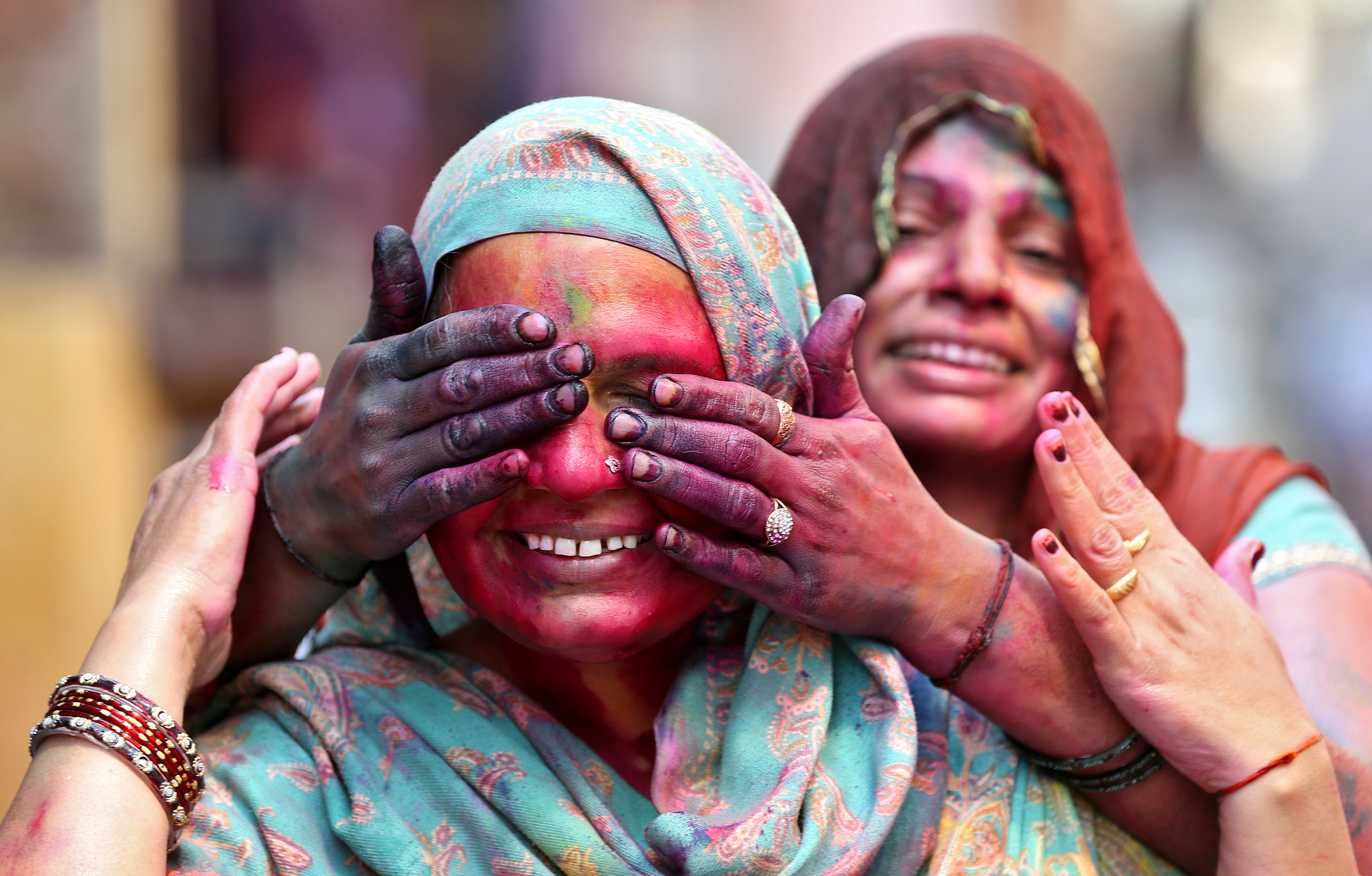 سيدة تضع الألوان على وجه صديقتها فى احتفالات الهند