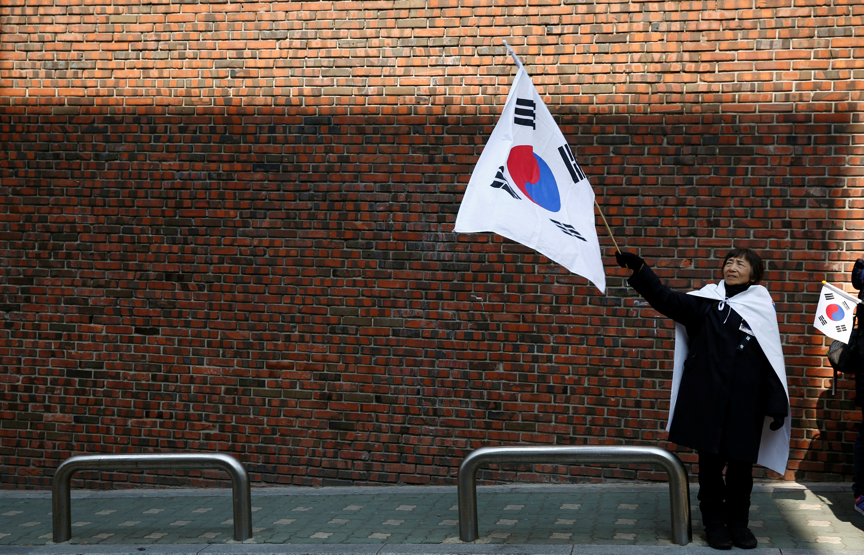 أحدى مؤيدى رئيسة كوريا الجنوبية المعزولة ترفع علم بلادها