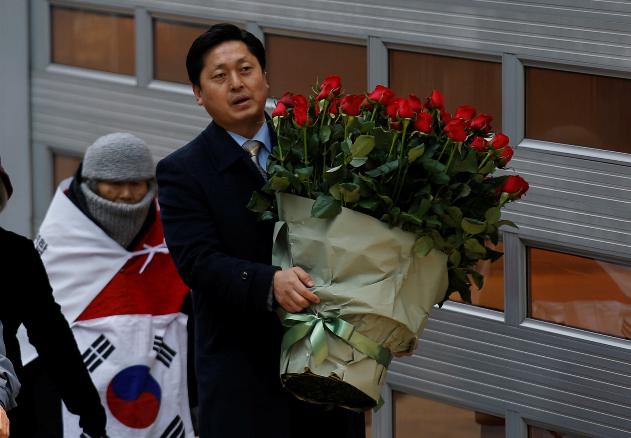 أحد مؤيدى رئيسة كوريا الجنوبية المعزولة يحمل باقة ورد أمام منزلها