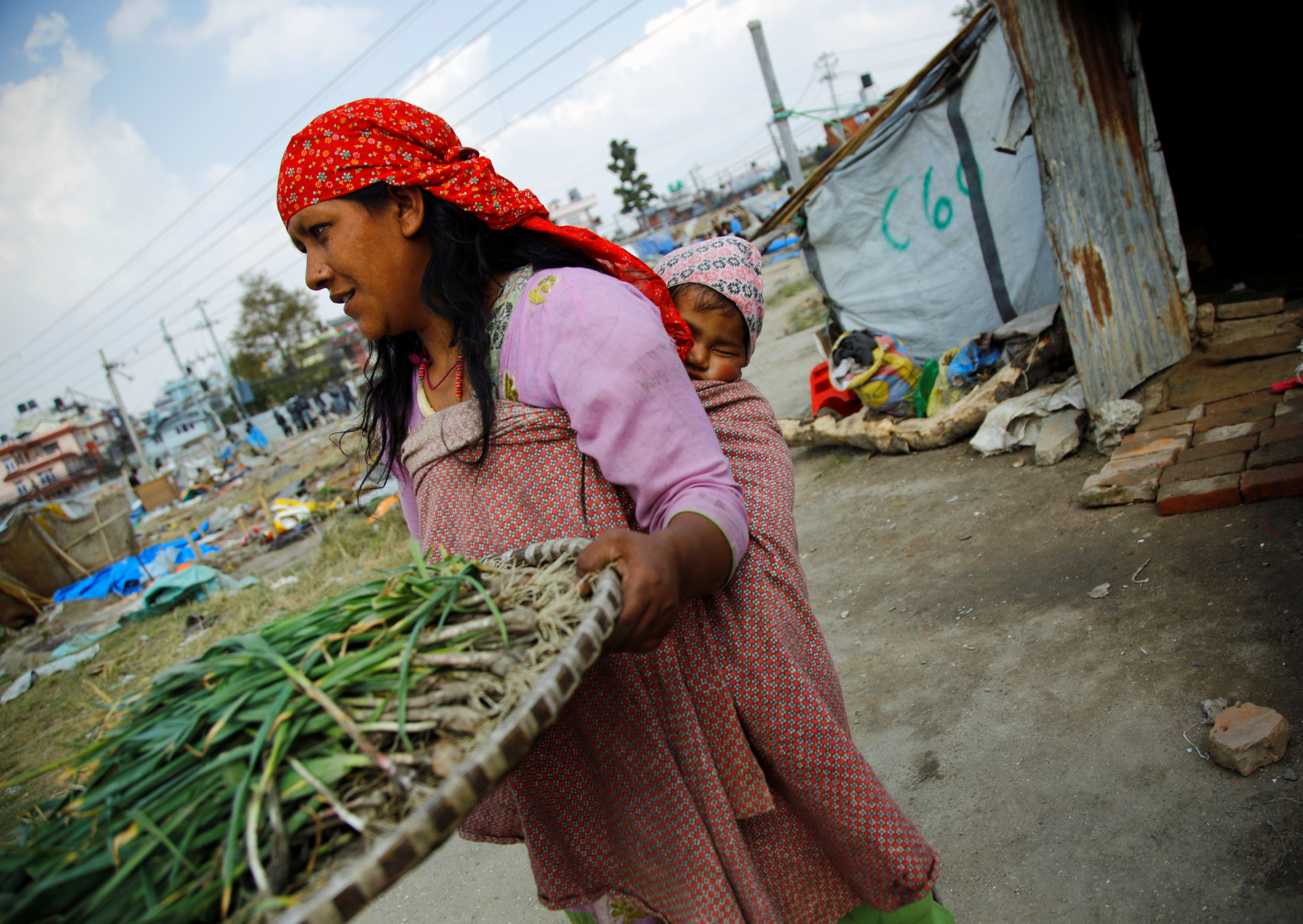 نيبالية تحمل طفلها قبل هدم مخيمها