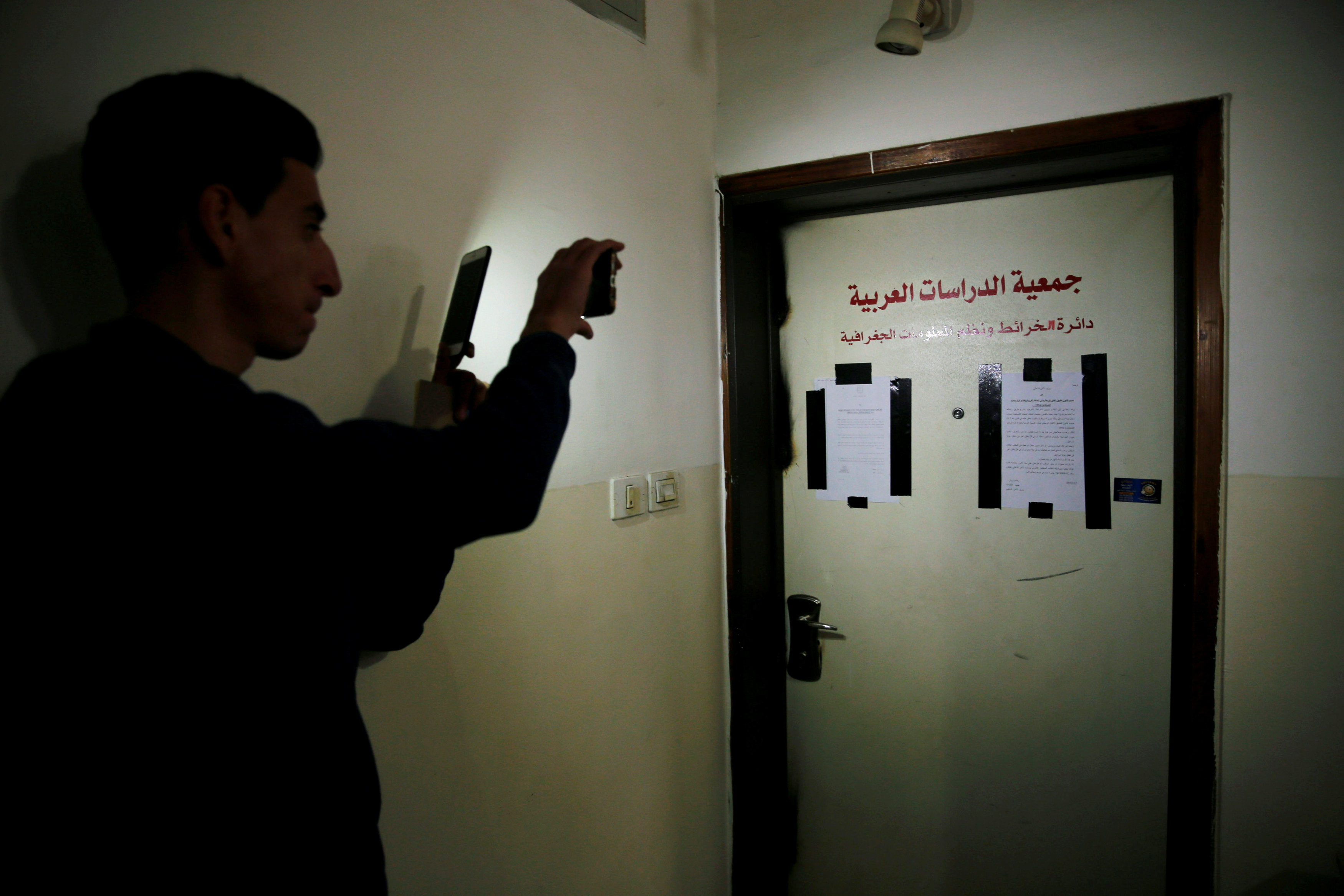 شاب يصور مقر المكتب عقب اغلاقه من قبل قوات الاحتلال