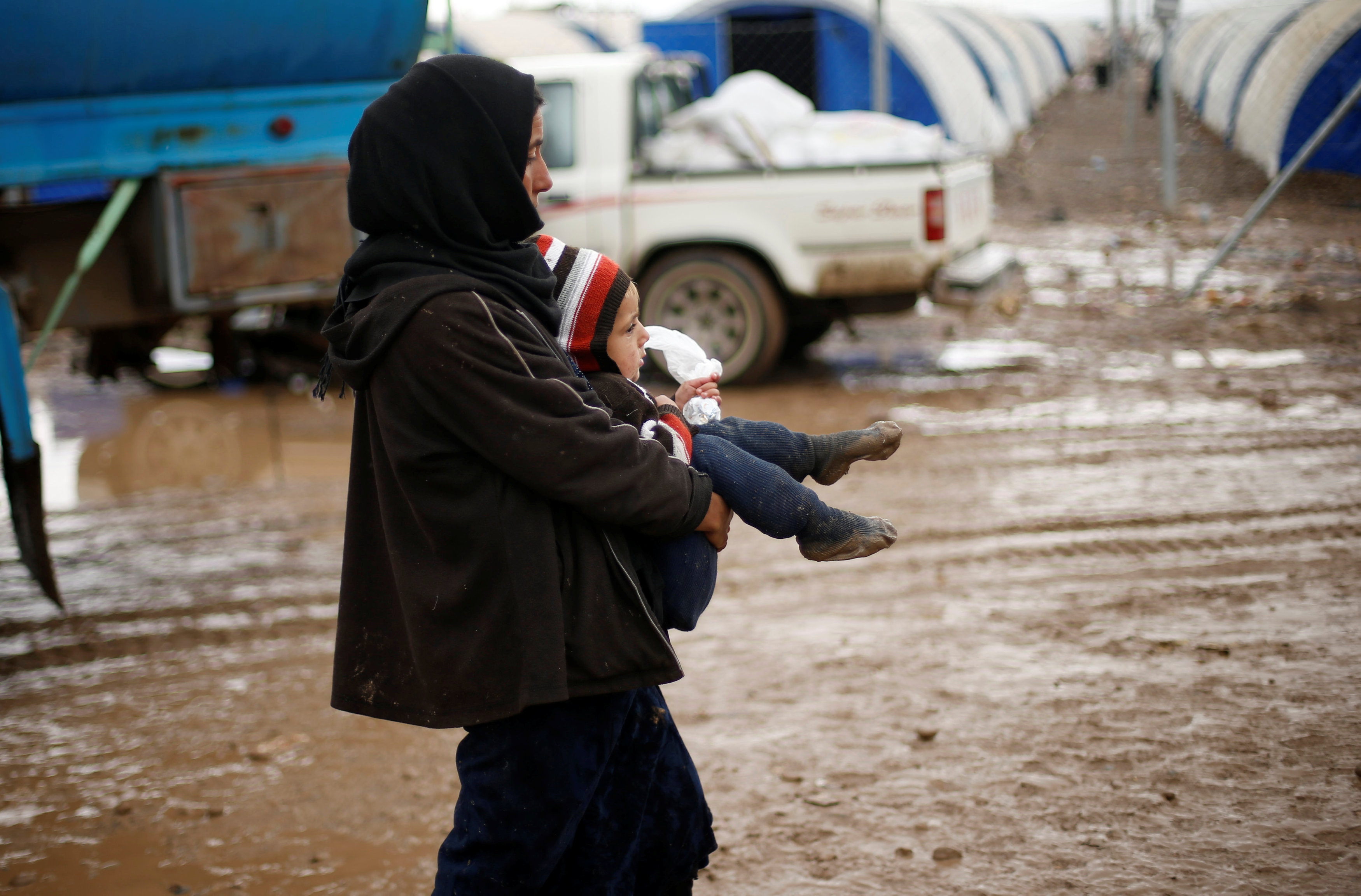 أم تحمل طفلها وسط المطر خلال فرارها من الموصل