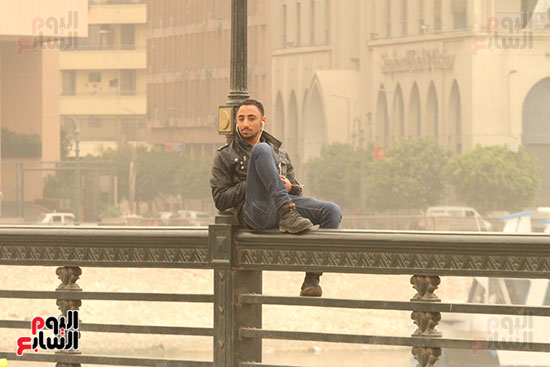مواطن يجلس فوق سور كوبرى قصر النيل