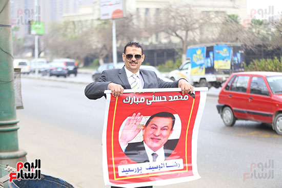 أحد أنصار مبارك يحمل صورته أمام مستشفى المعادى العسكرى 