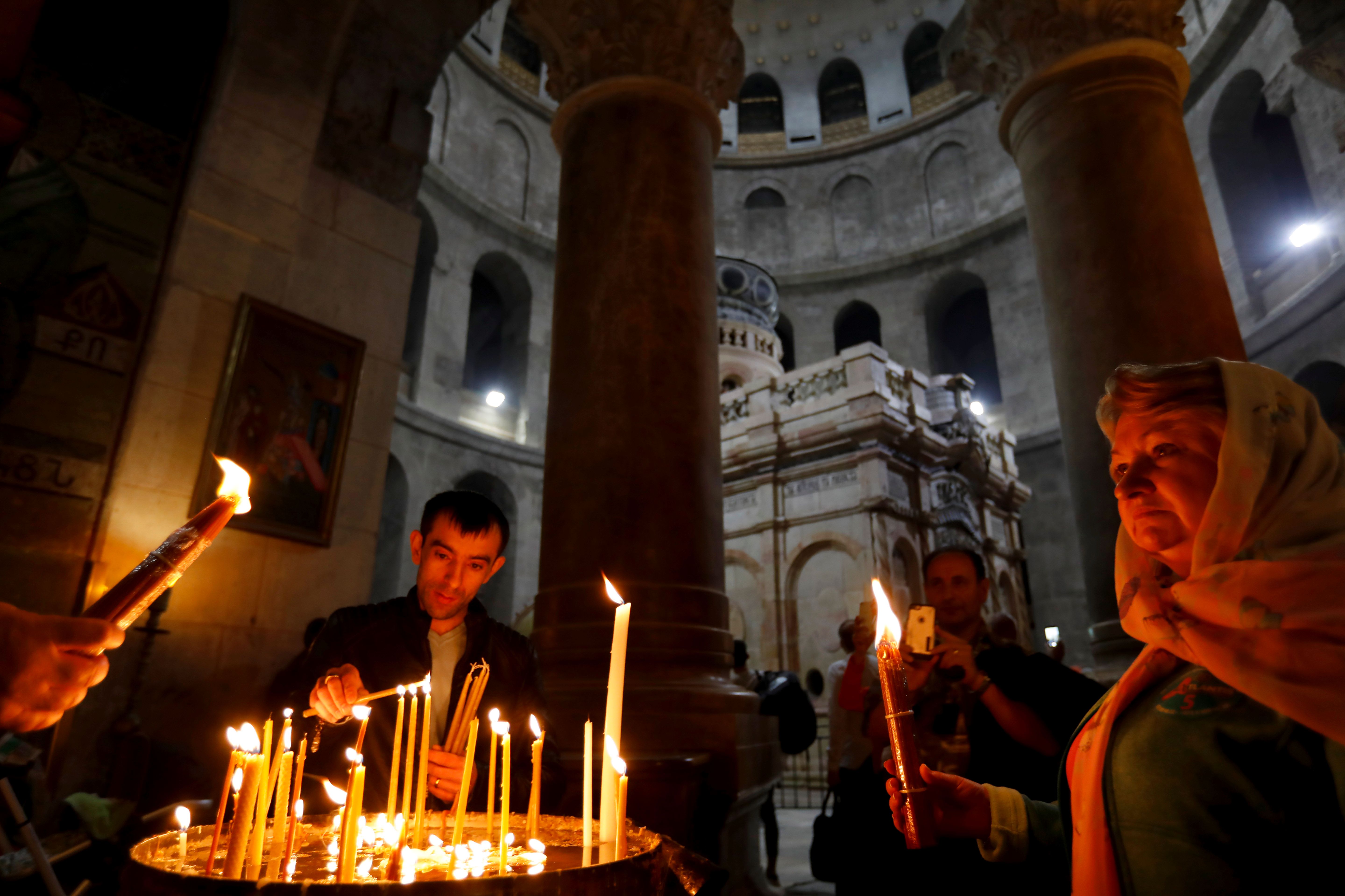 المصلون المسيحيون يشعلون الشموع حول قبر المسيح