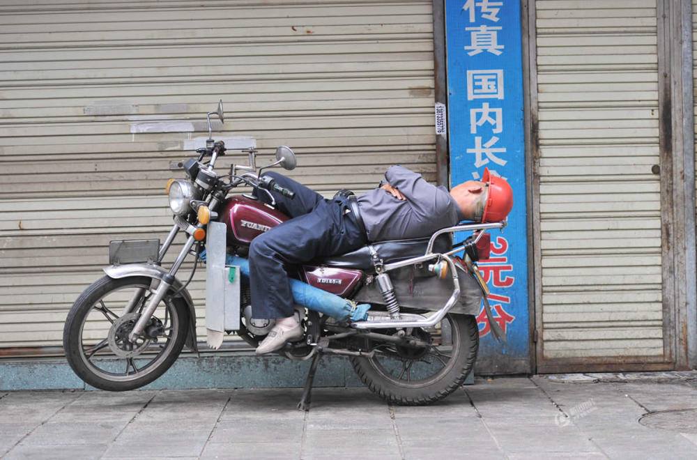 عامل صينى ينام على دراجة نارية
