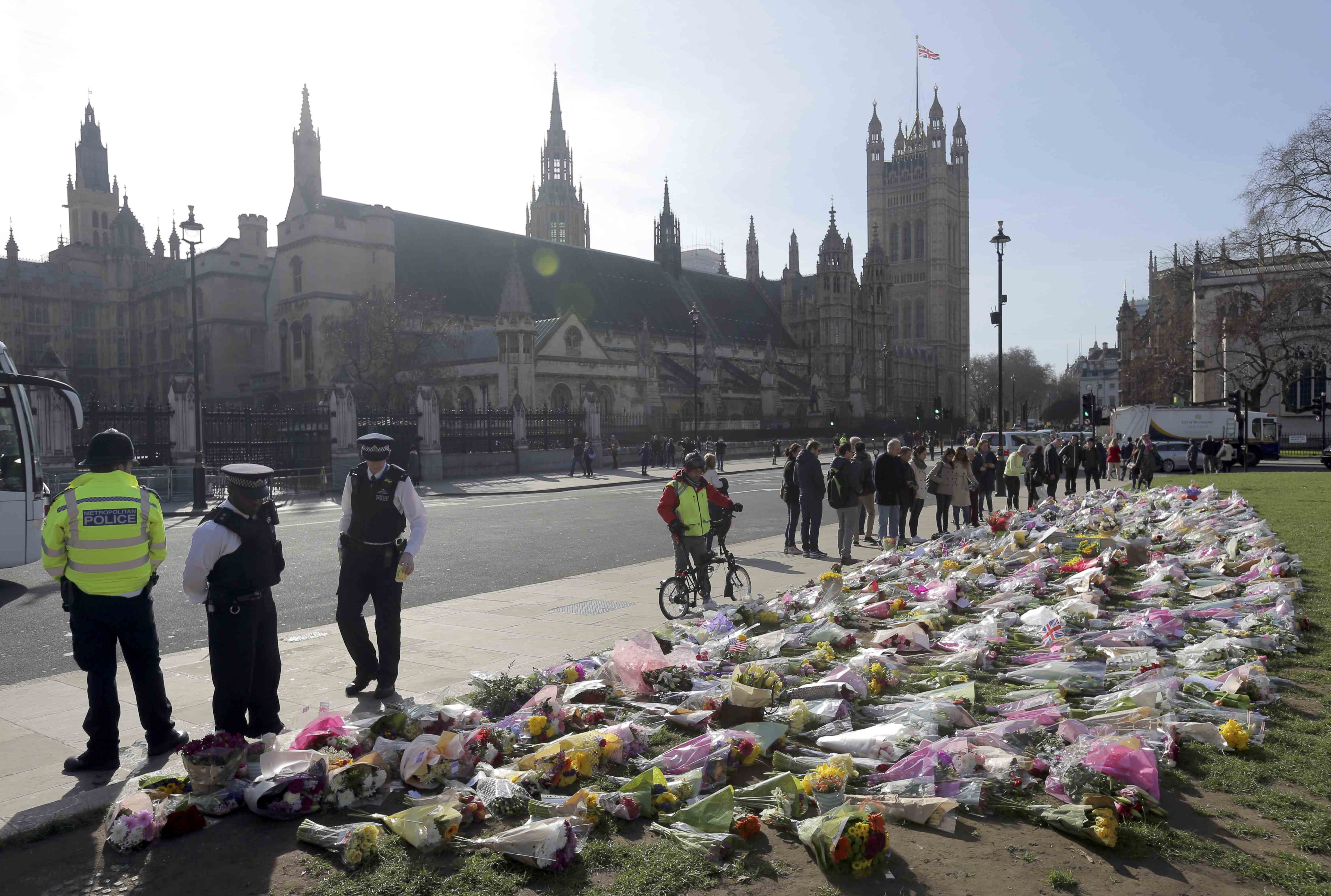 الشرطة البريطانية ومواطنون بجوار الزهور فى ساحة البرلمان