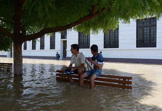 مواطنين يحملون أمتعتهم فى محاولة لعبور مياة الفيضان