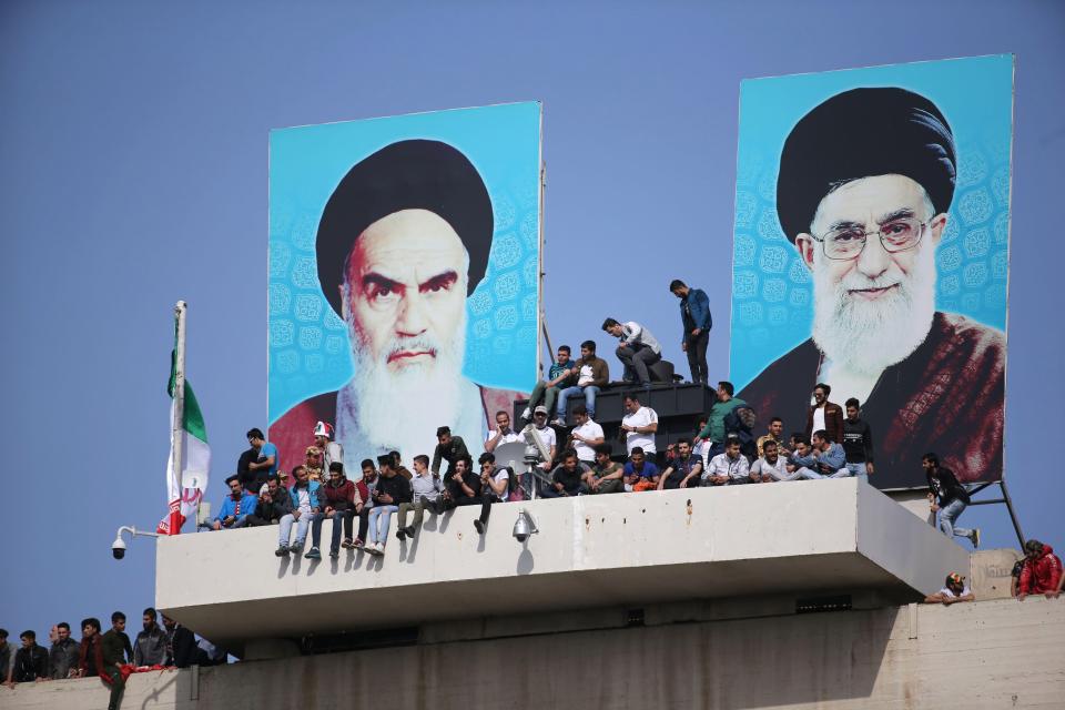 الجماهير تجلس بين صورتى زعيمى إيران السابق آية الله الخومينى والحالى على خامنئى