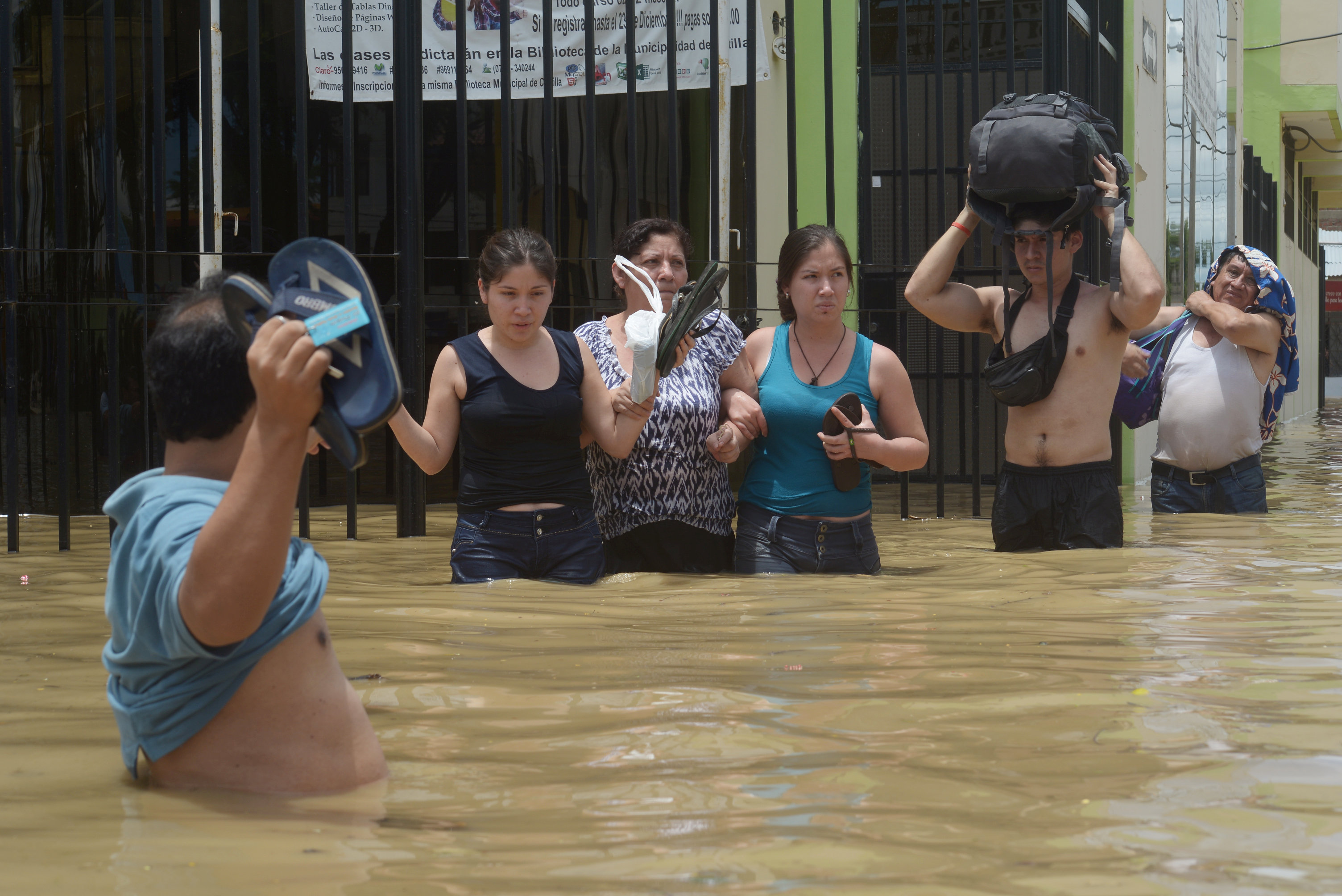 مواطنين يحملون أمتعتهم فى محاولة لعبور مياة الفيضان