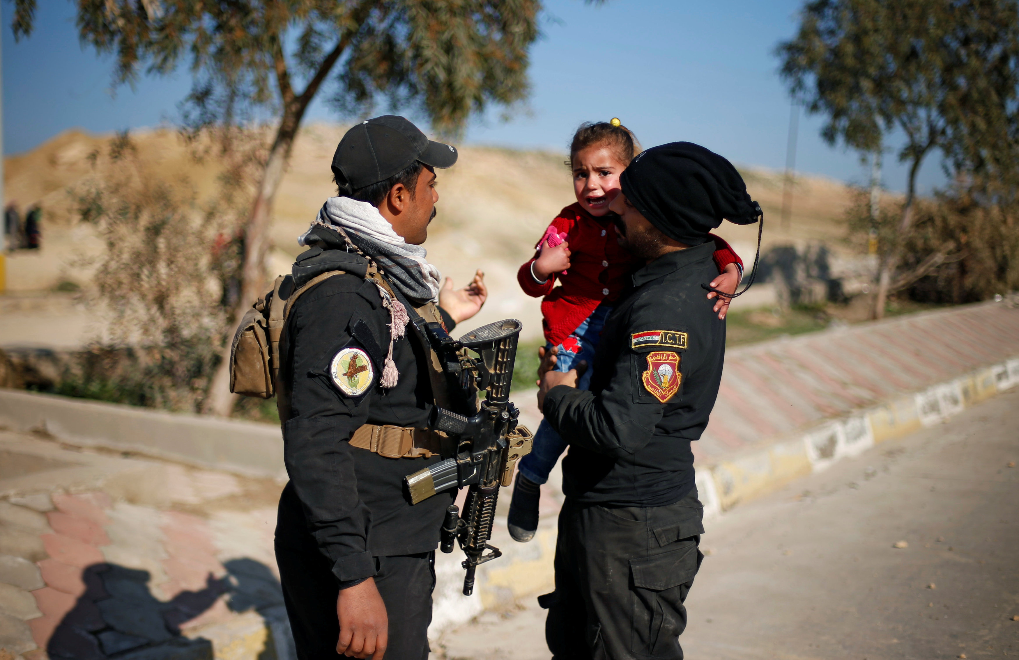 رجال الشرطة العراقية يهدأون طفلة خائفة