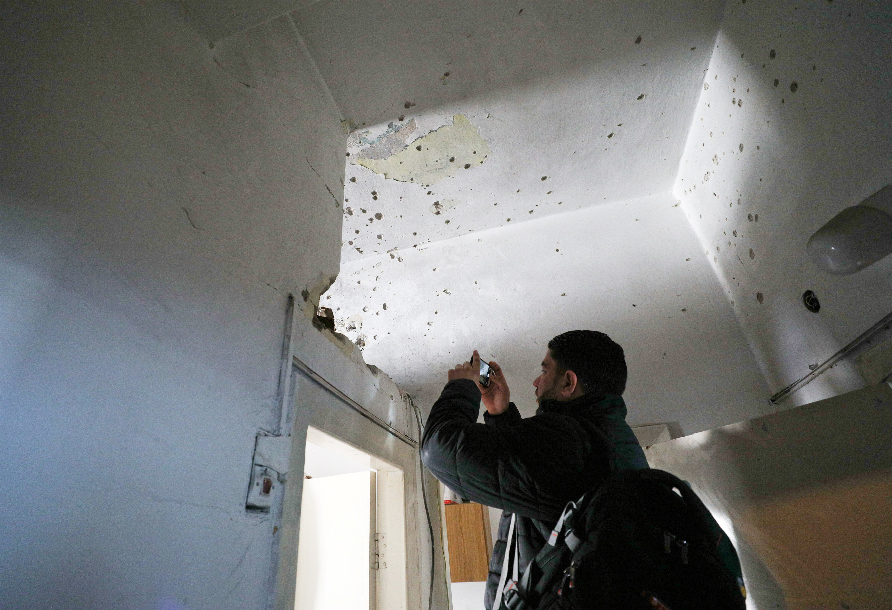 شاب يصور اثار الرصاص على حوائط منزل الشهيد الفلسطينى
