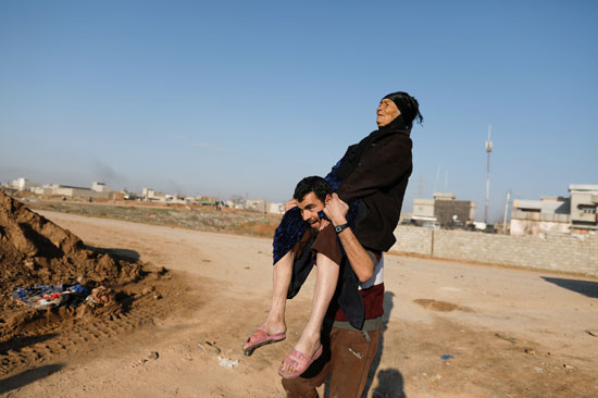 شاب يحمل سيدة عجوز على كتفيه فى العراق