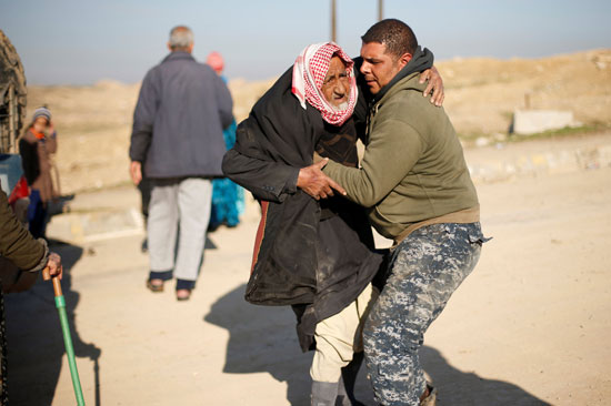 شاب يحمل رجلا عجوزا نازحا من الموصل
