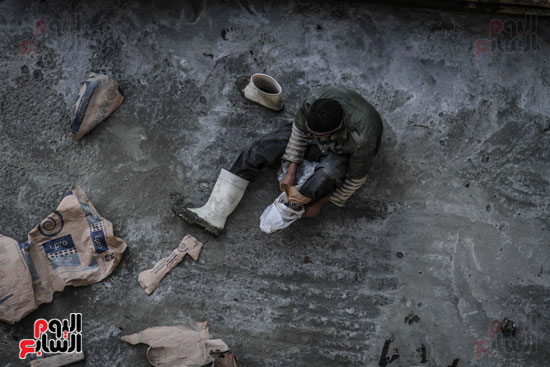 أحد عمال الخرسانة يستعد للعمل ويرتدى الحذاء