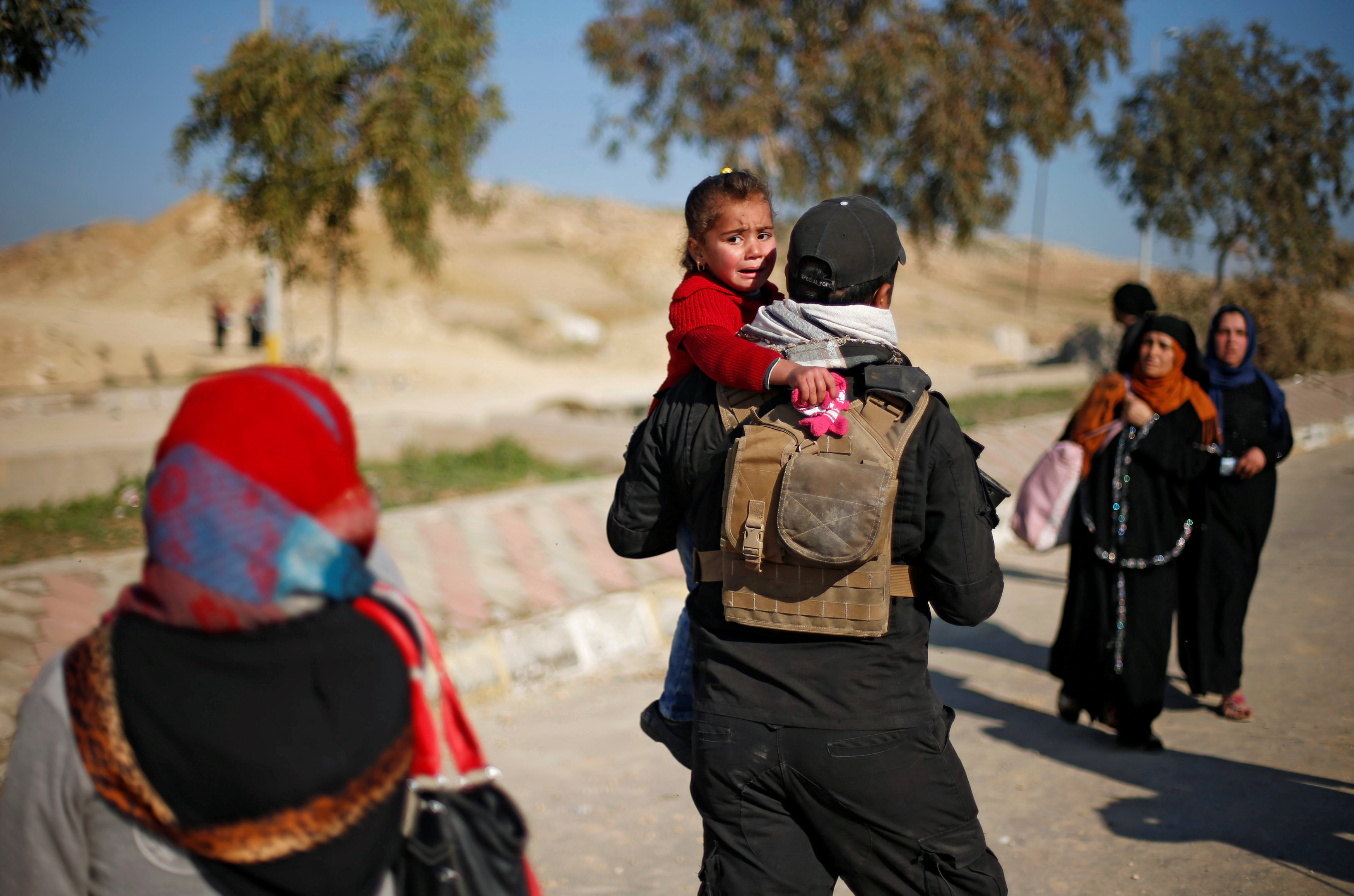 فرد من الشرطة العراقية يحمل طفلها عن والدتها لنقلها لمكان أمن