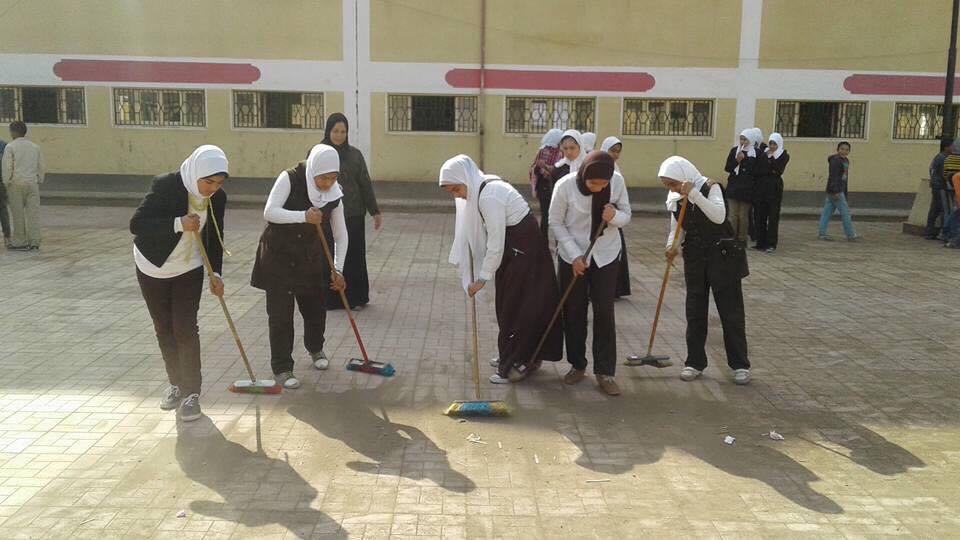 الطالبات ينظفن المدرسة من الرمال
