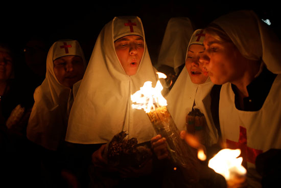  راهبات يشعلن الشموع خلال احتفالات عيد الفصح بكنيسة القبر المقدس