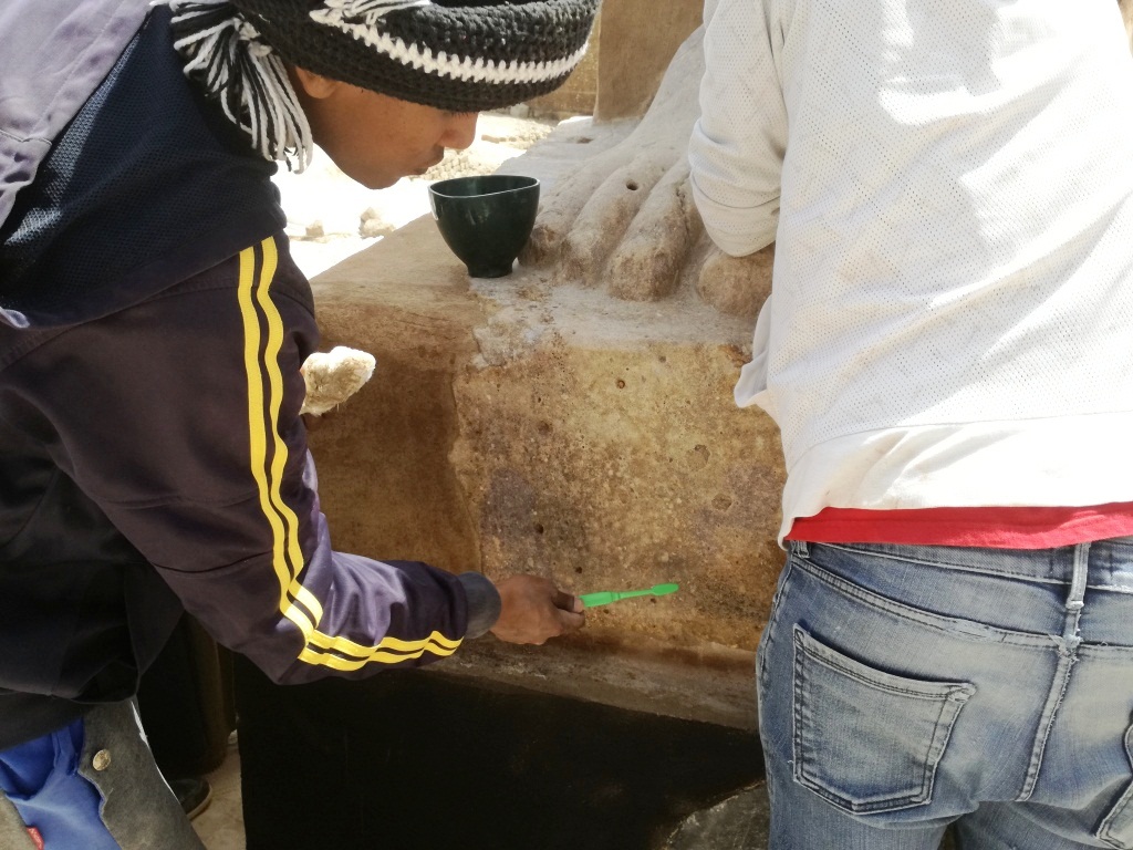 3- شاب مرمم يستخدم الفرشاة لتنظيف تمثال لأحد ملوك الفراعنة