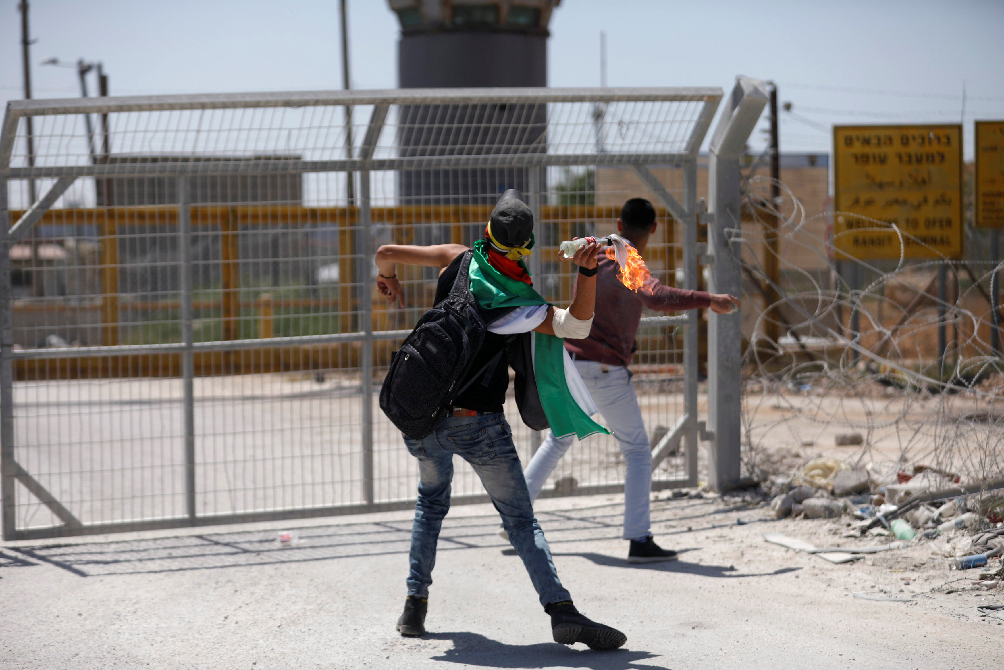 متظاهر فلسطينى يثير  زجاجة حارقة تجاه القوات الاسرائيلية
