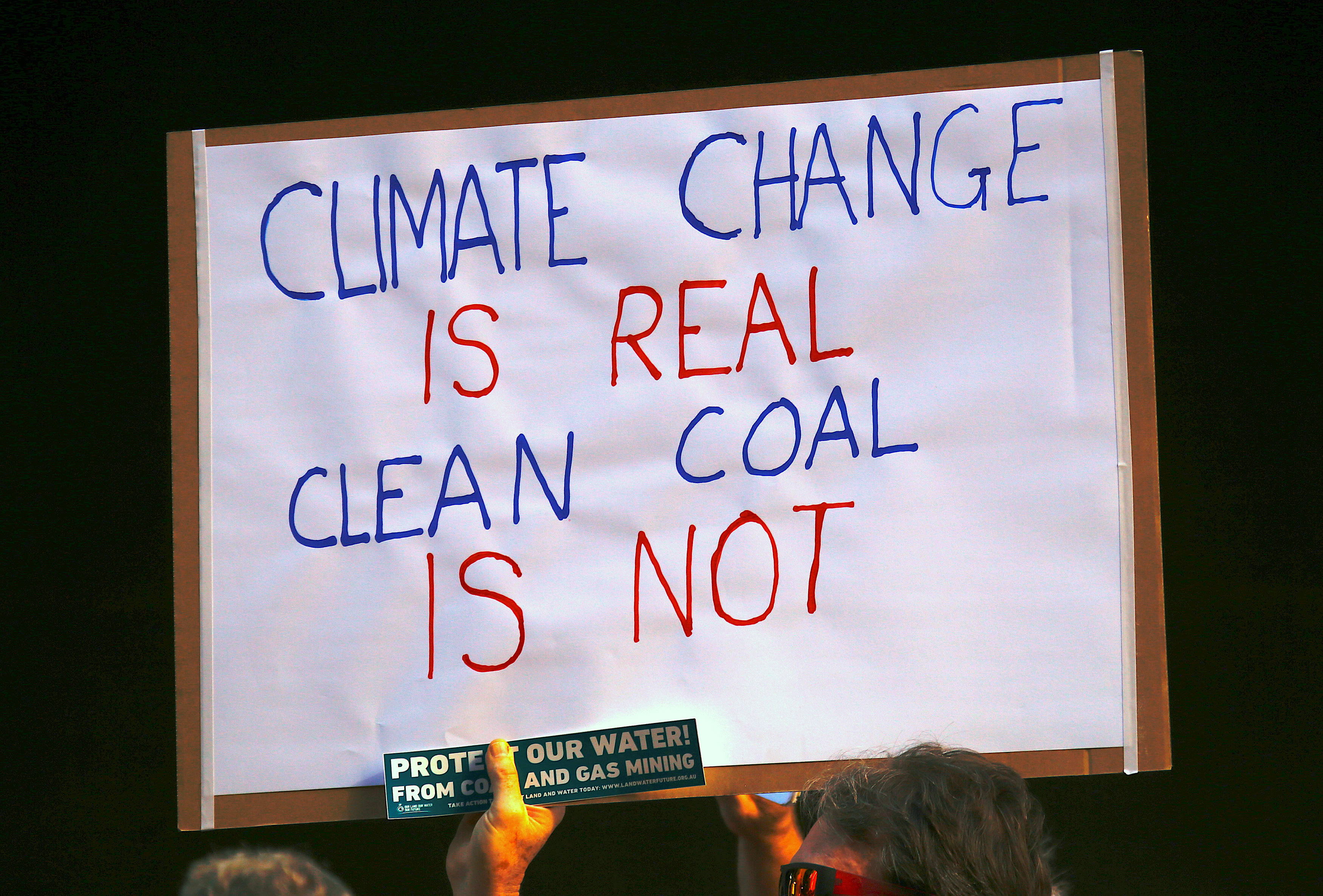 لافتة مكتوب عليها تغير المناخ حقيقى والفحم النظيف غير حقيقى