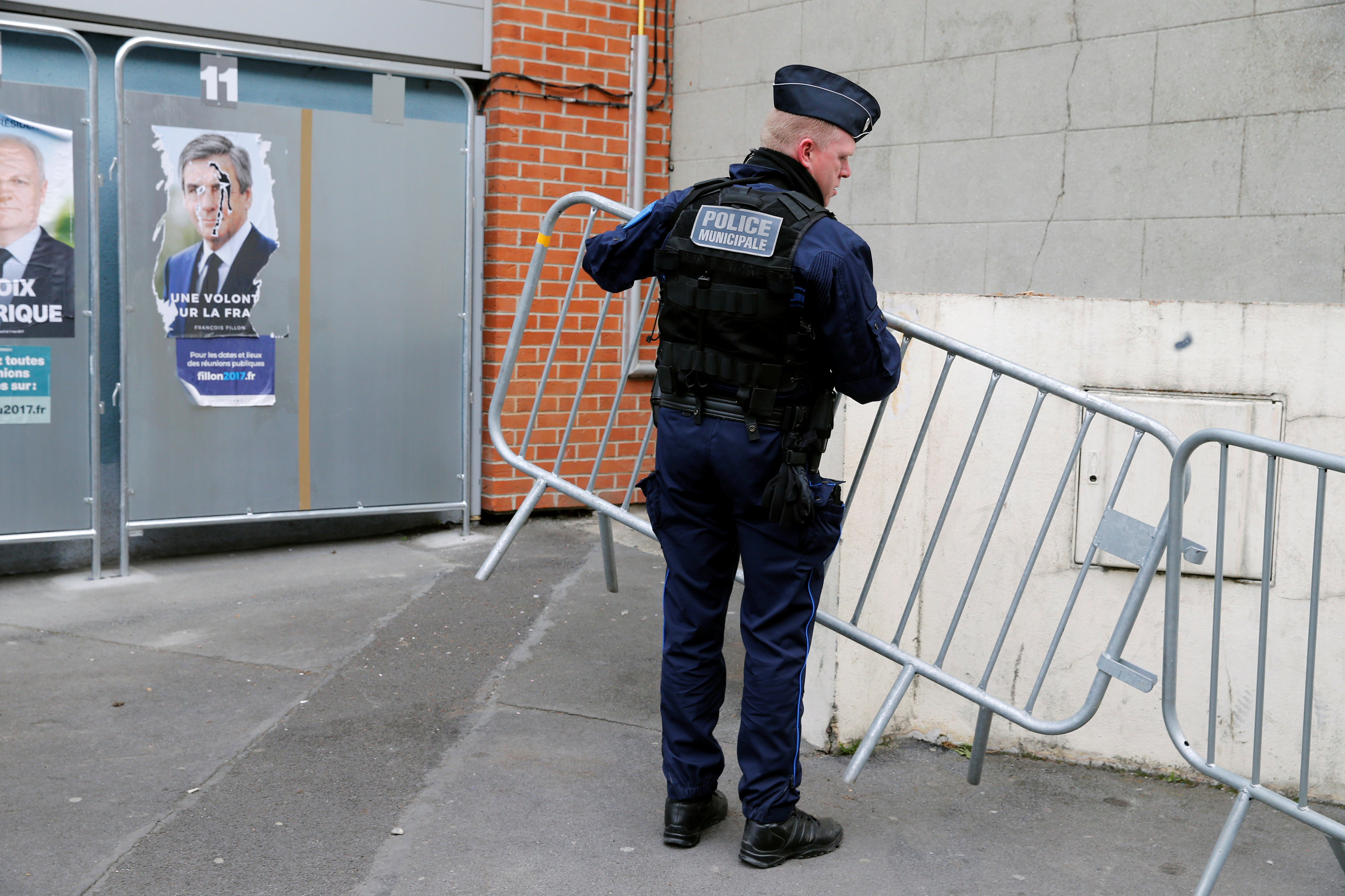 شرطى فرنسى يضع الحواجز الحديدية بمحيط لجنة انتخابية