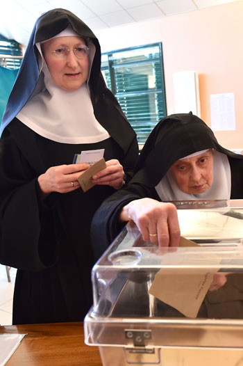 راهبة تضع ورقة التصويت داخل صندوق الاقتراع