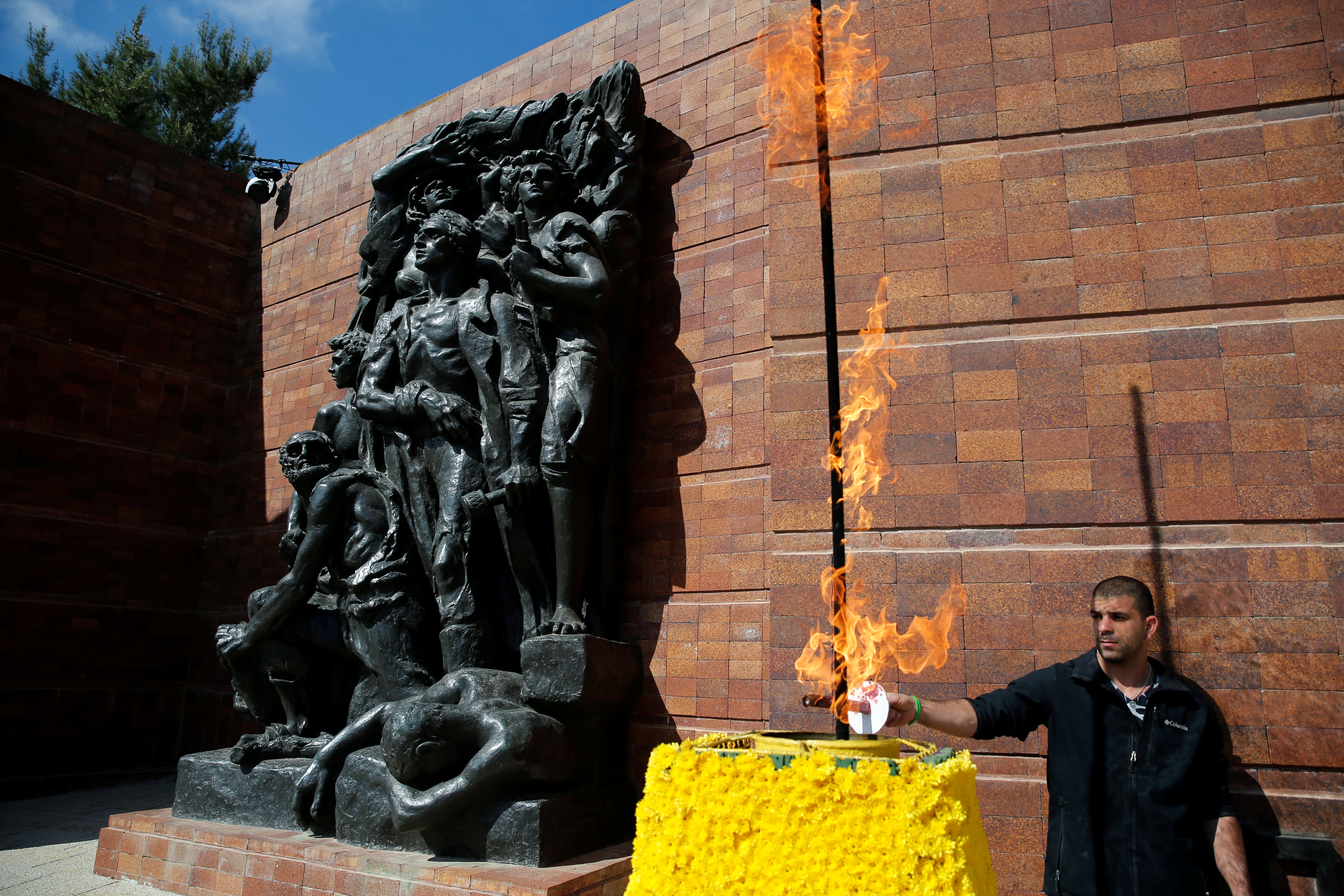 رجل يشعل النار أمام النصب التذكارى للمحرقة