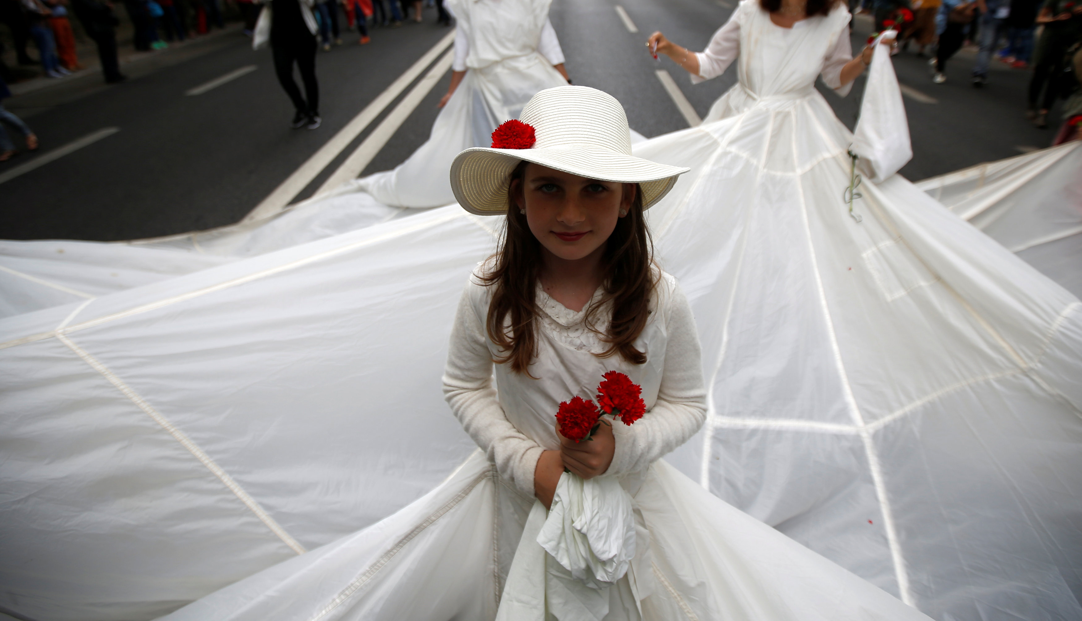 فتيات ترتدين الفتساتين البيضاء خلال إحياء ذكرى ثورة القرنفل