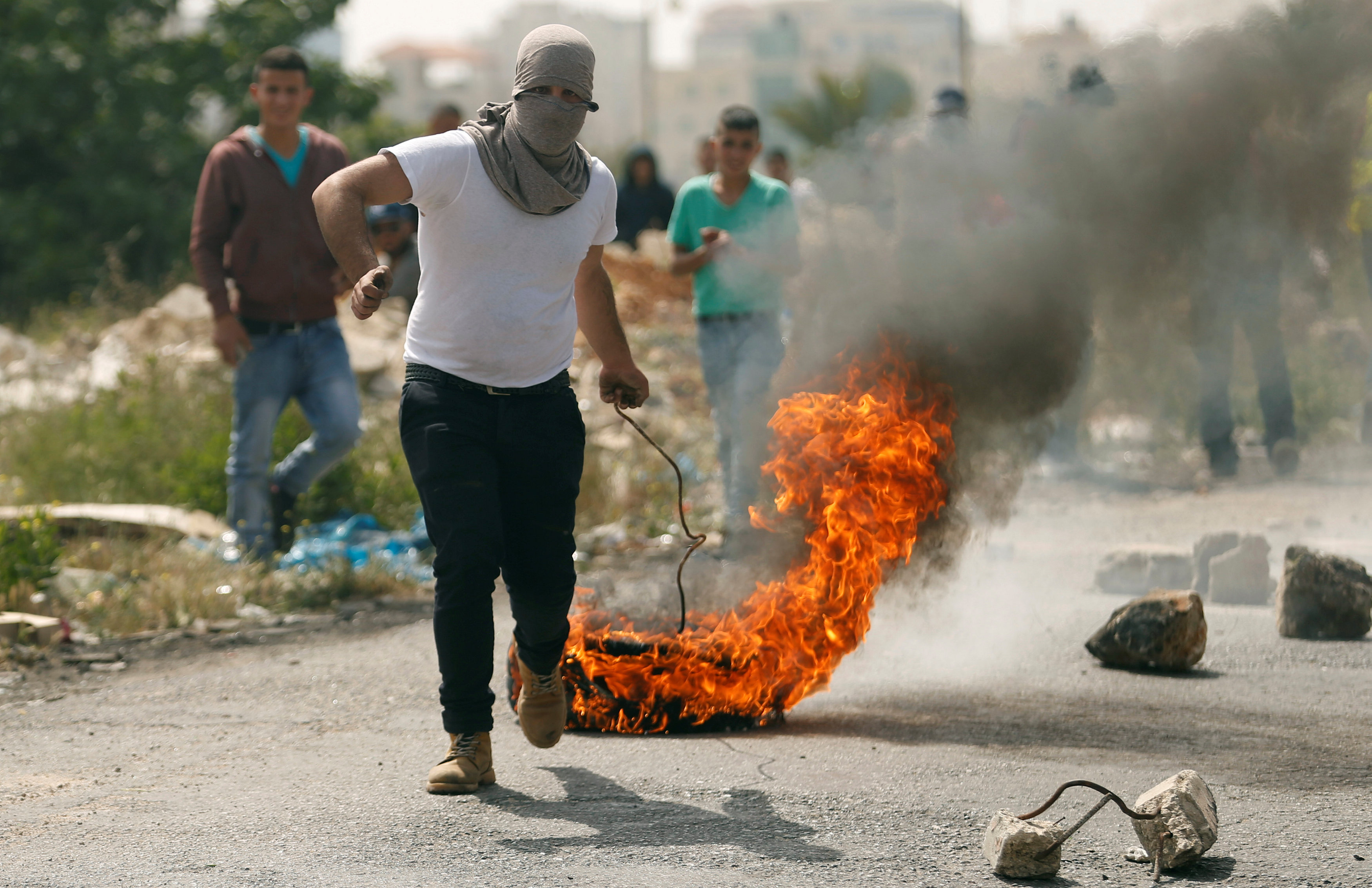 فلسطينى يجر كاوتش محترق لحجب رؤية قوات الاحتلال