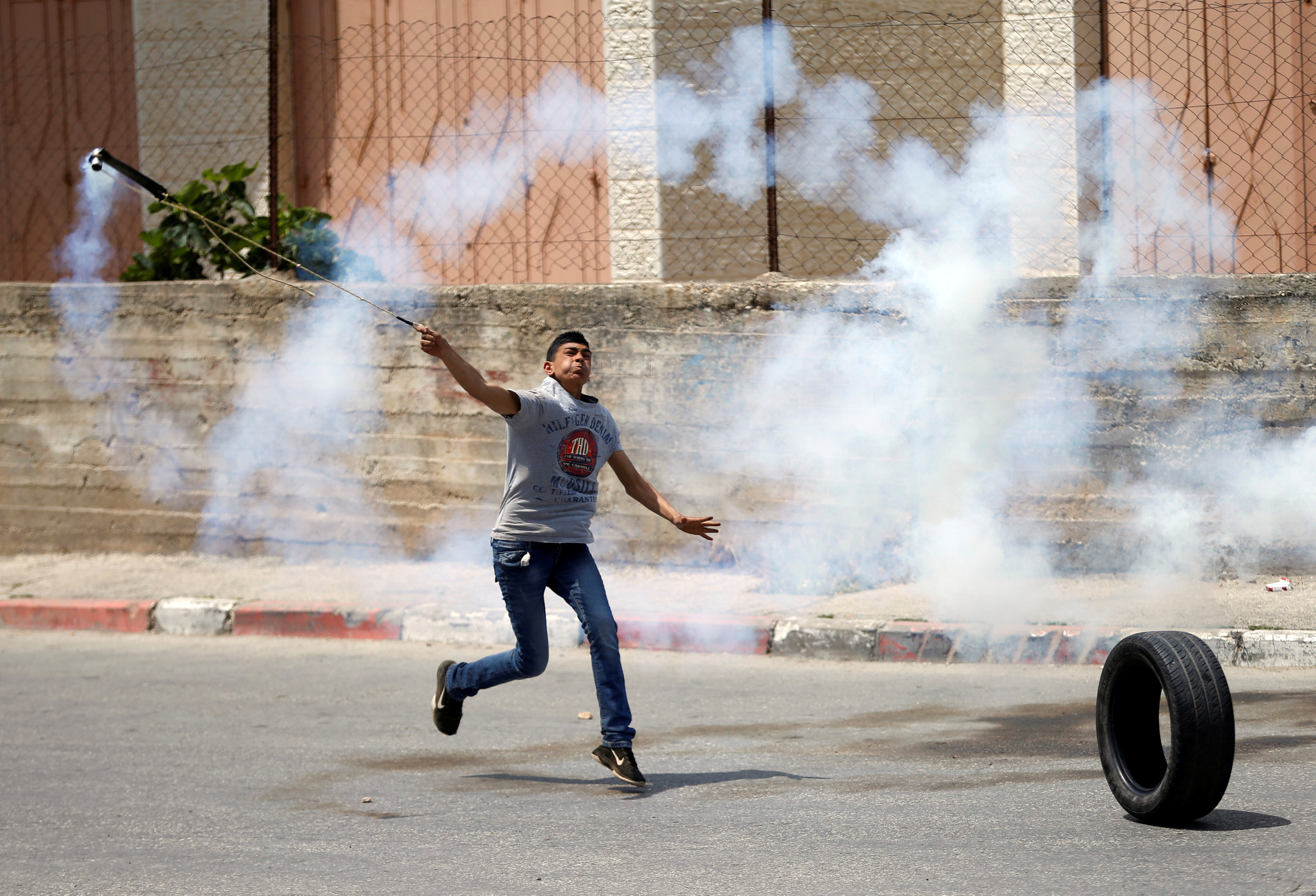 شاب فلسطينى يشعل الخشب لتخفيف حدة تأثير قنابل الغاز