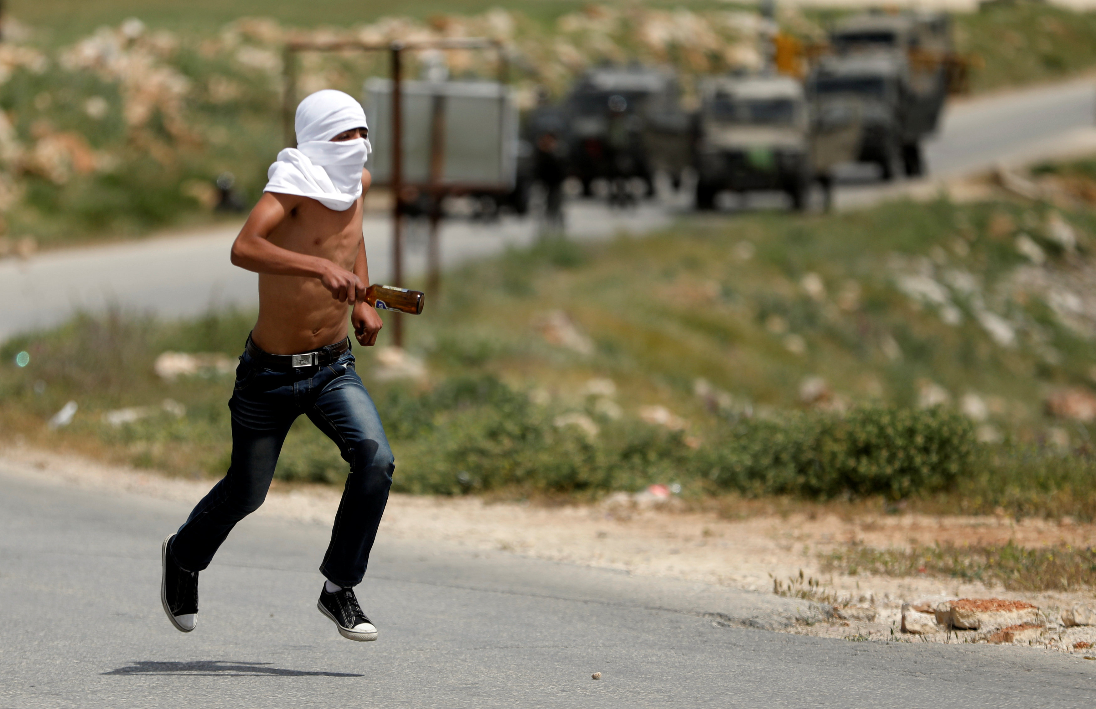 متظاهر فلسطينى وخلفة مركبات قوات الاحتلال الإسرائيلى