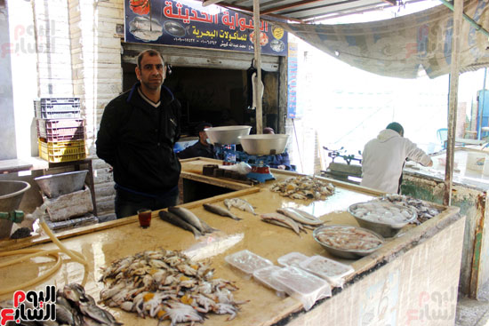 احد التجار  يقف أمام طاولة السمك بسوق شارع الجيش 