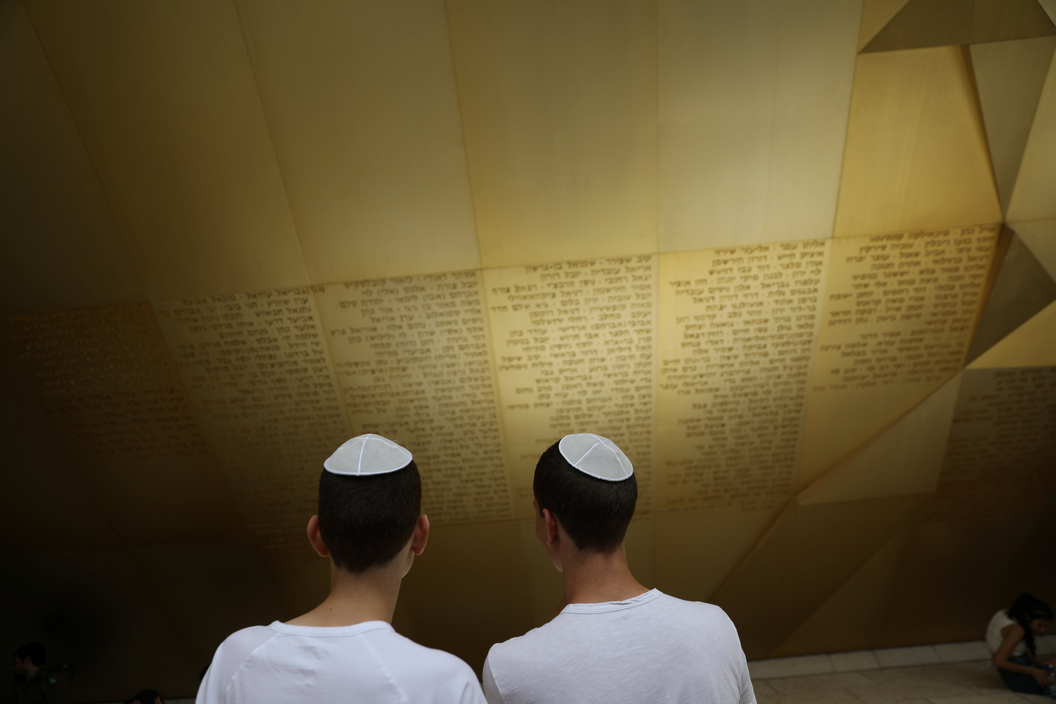 شابان إسرائيليان يطلعان على كتابات جدران المقبرة العسكرية