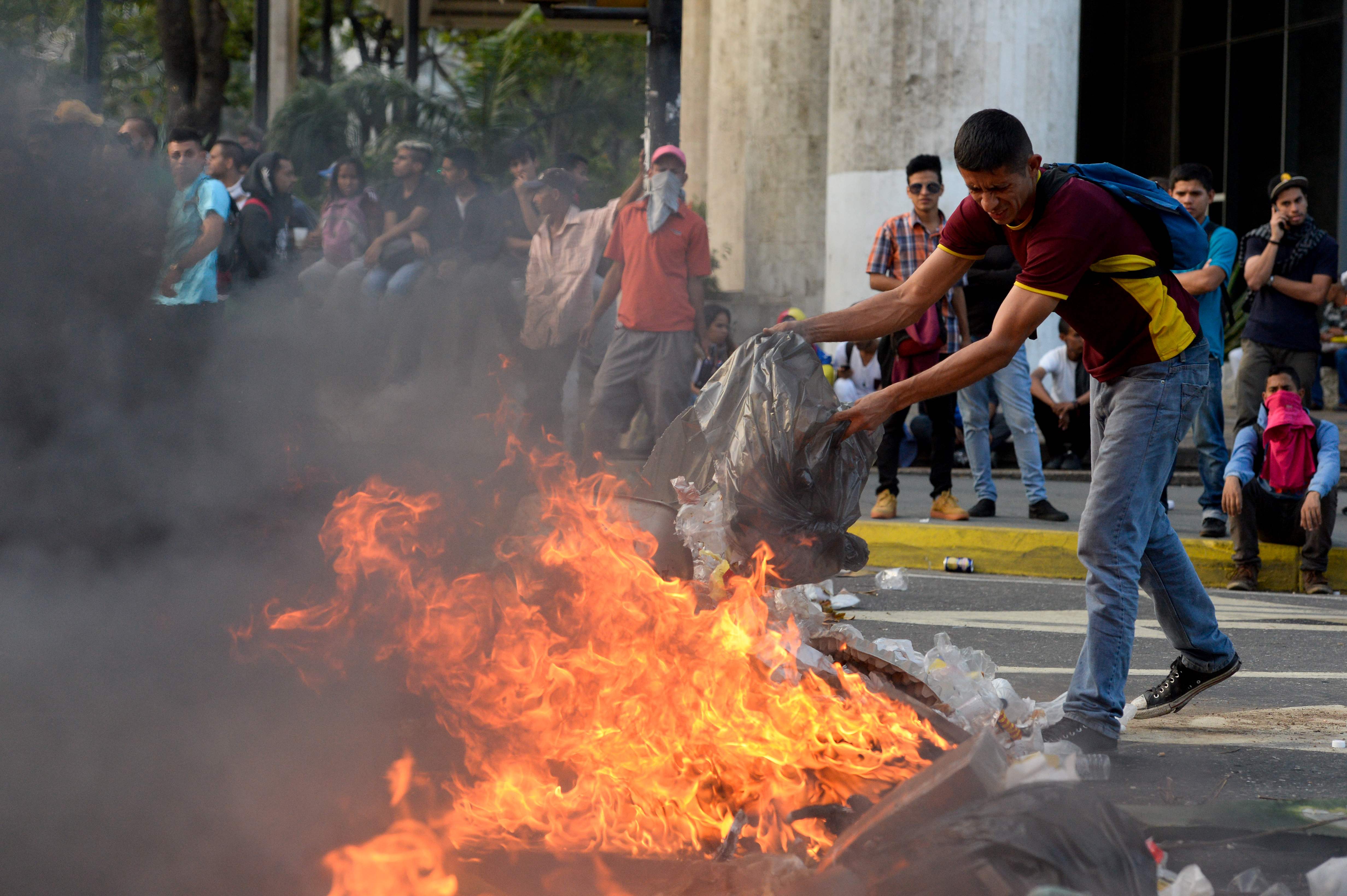 أحد المحتجين يلقى القمامة على النيران