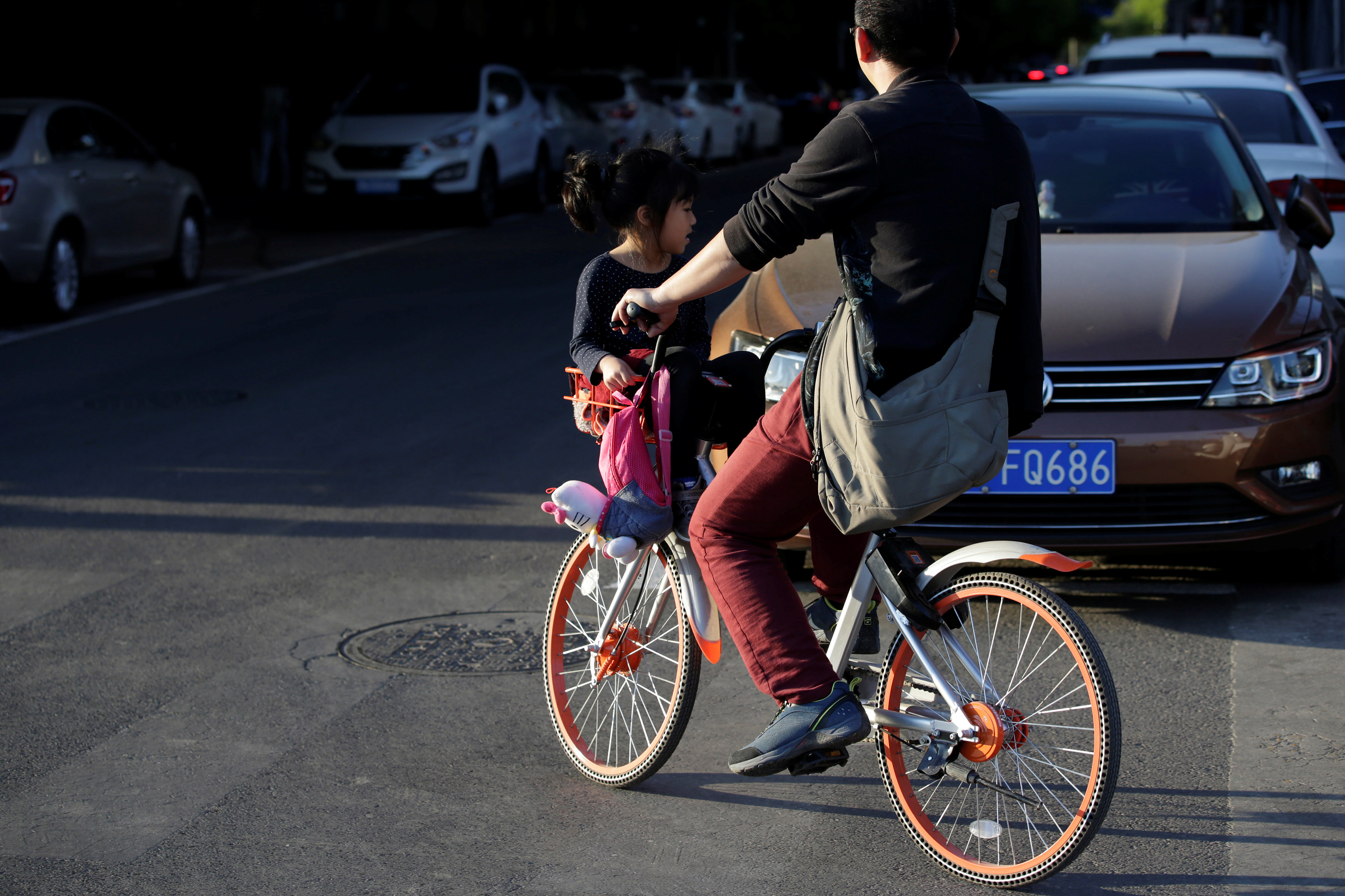 مواطن يحمل طفلة امامة على الدراجة