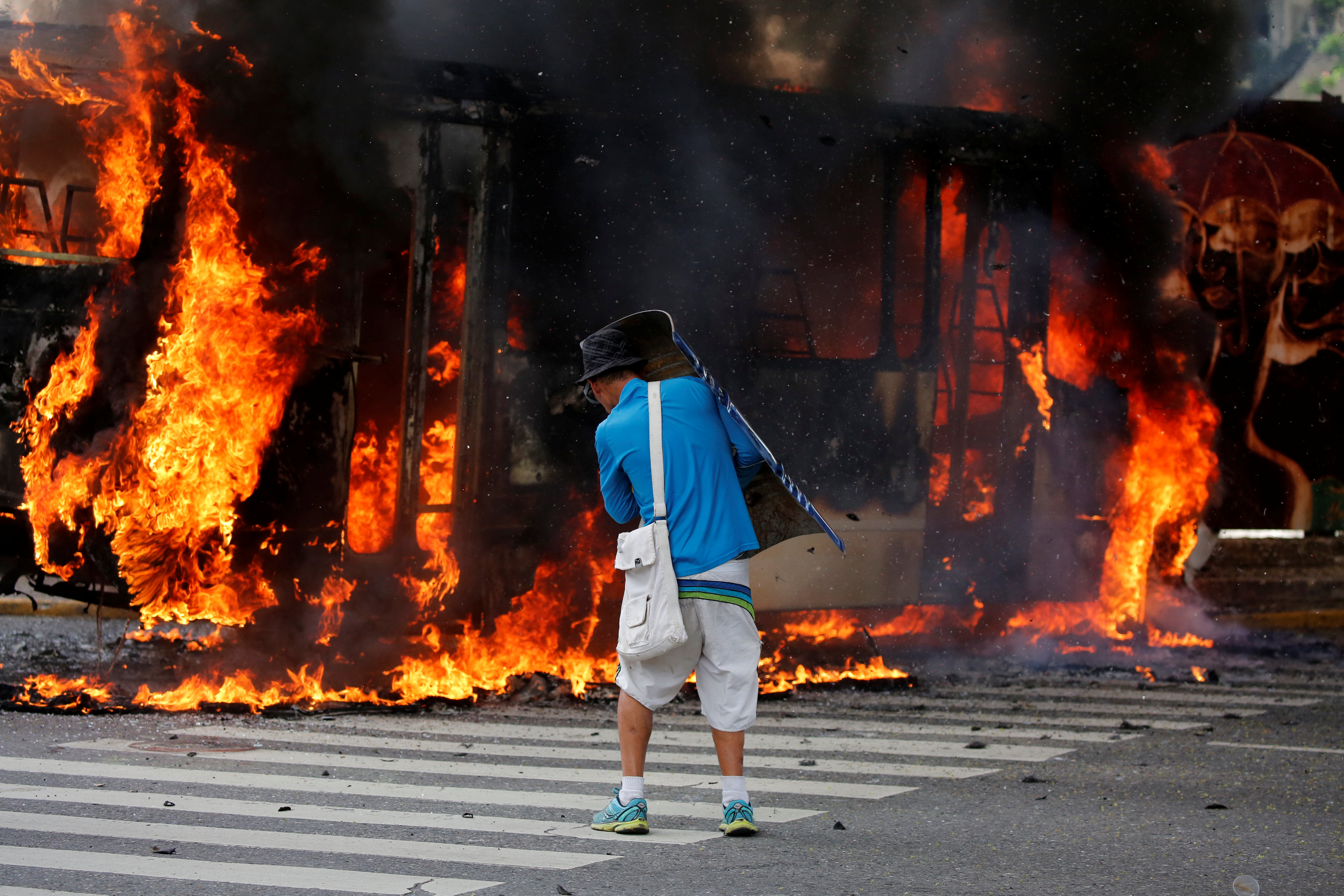 مواطن يقف بجوار السيارة المحترقة